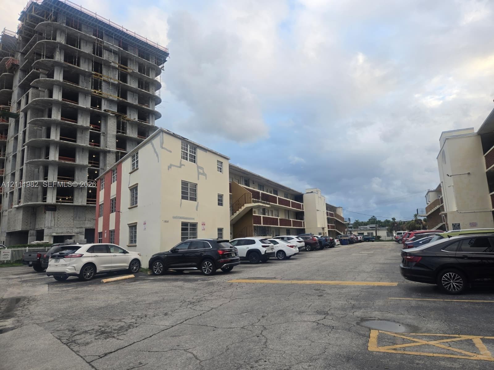 Multi-story residential building with exterior stairwells, stucco finish, and dedicated asphalt surface parking