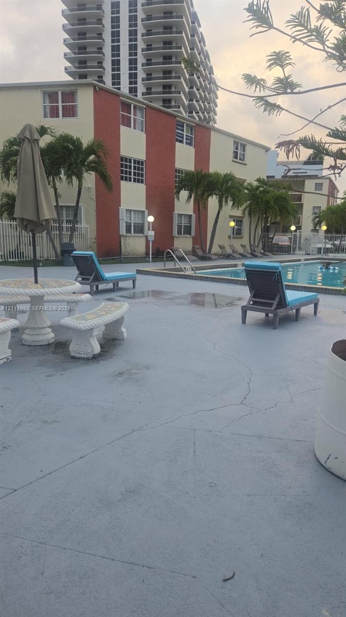 Swimming pool with concrete decking, palm trees, and multi-story building exterior