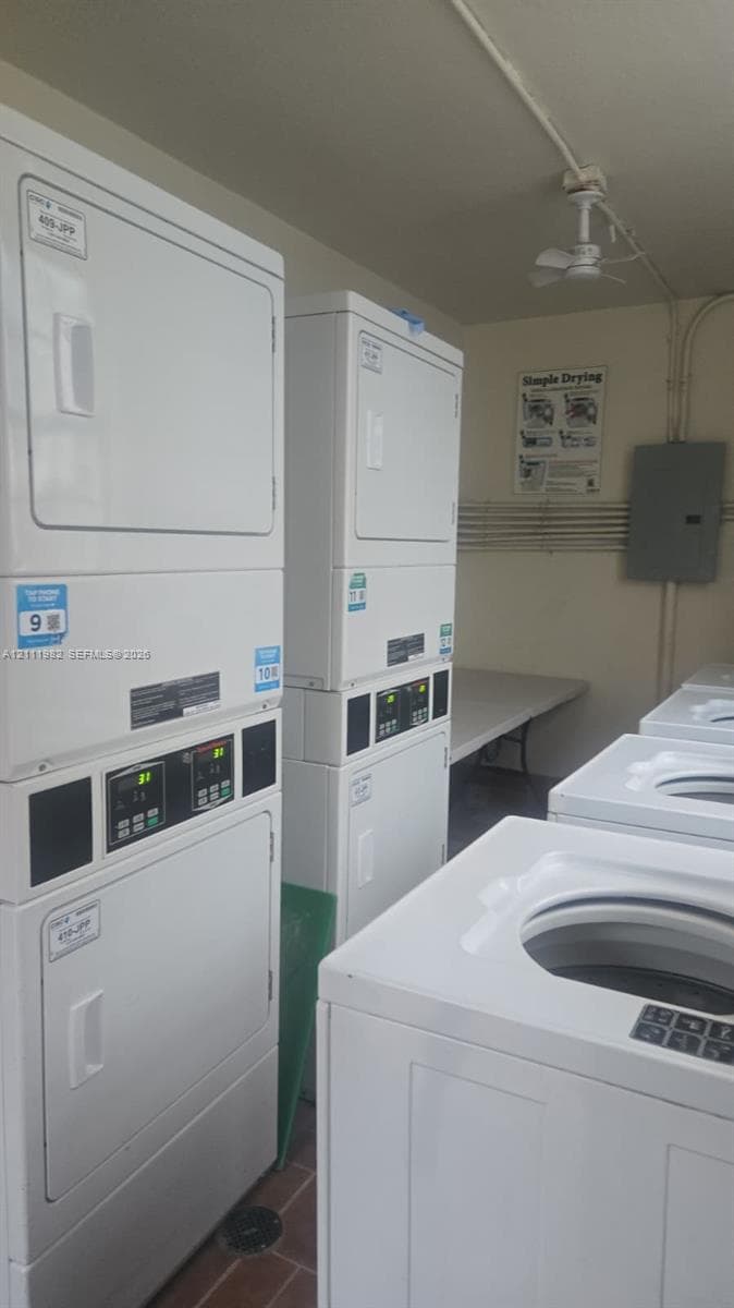 Laundry facility featuring multiple stacked commercial-grade washer and dryer units, a folding table, and tiled flooring