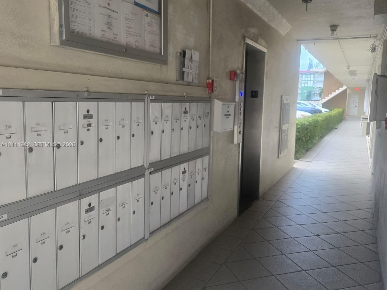 Centralized wall-mounted metal mailboxes, elevator access, and covered tiled walkway