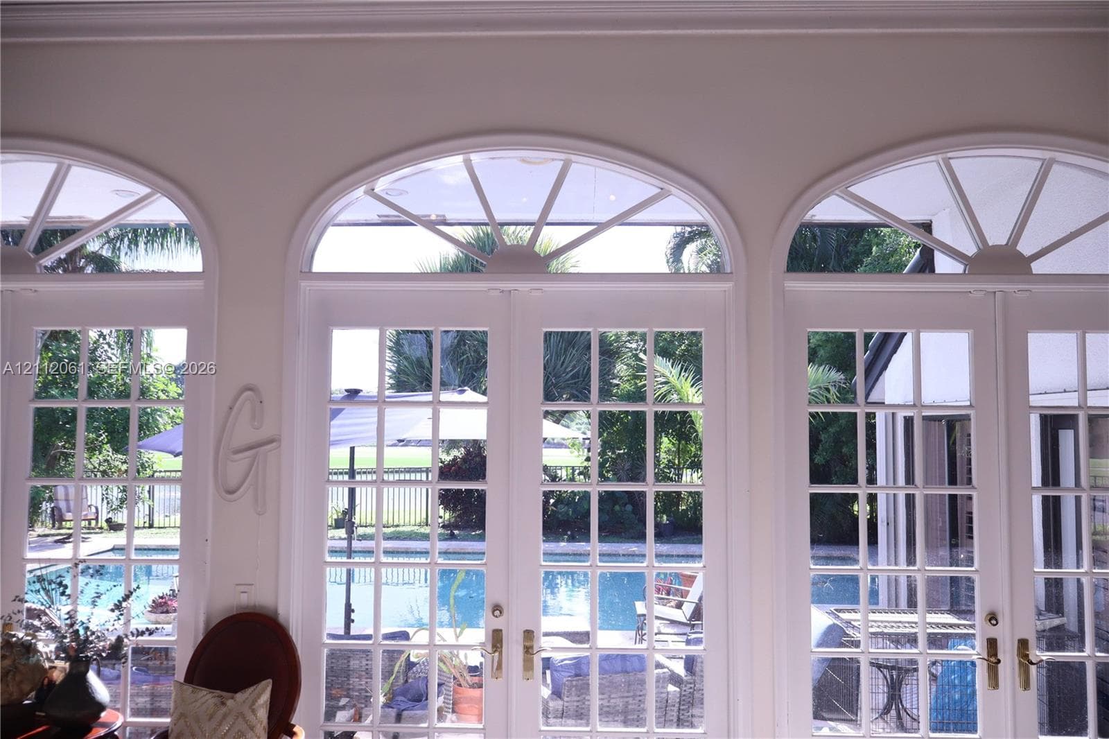 Triple set of French doors featuring multi-pane glass, arched transoms with radial muntins, and metallic hardware