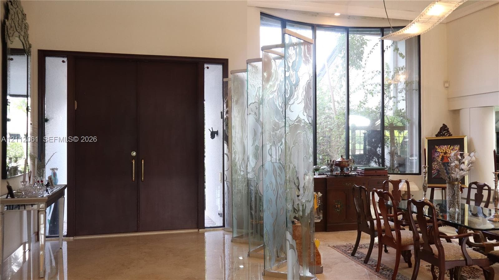 Double-door entry with sidelights, high ceilings, expansive floor-to-ceiling curved windows, and decorative frosted glass panels