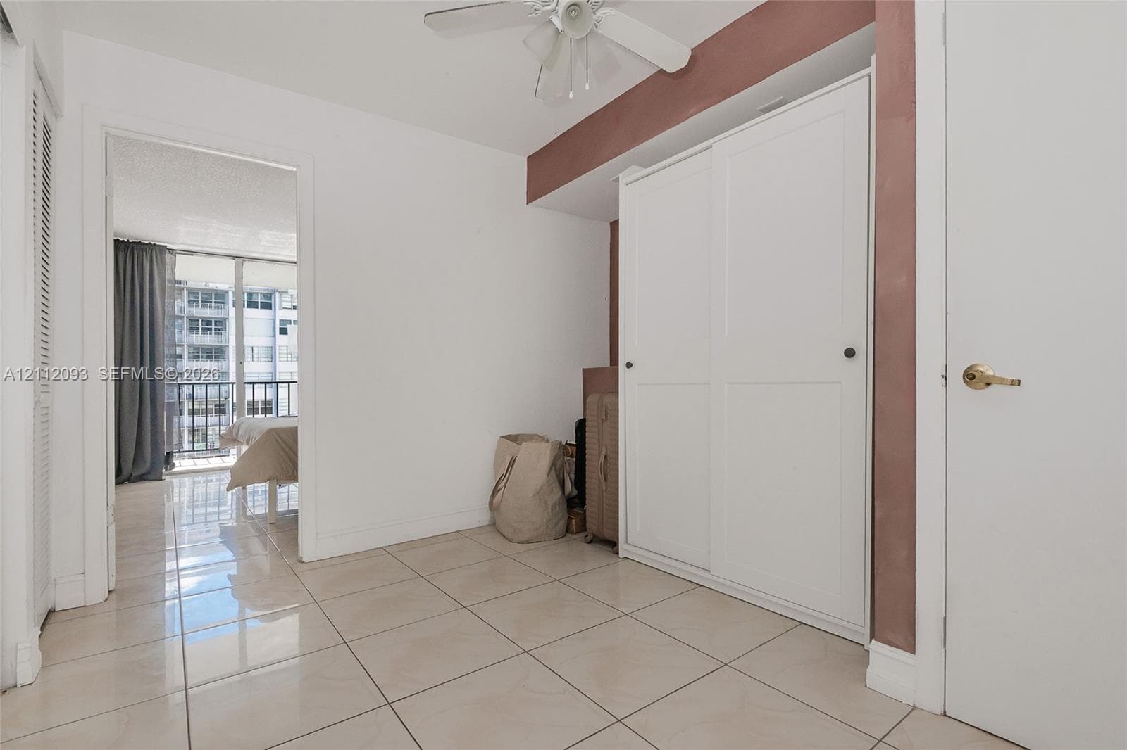 Room featuring large-format ceramic tile flooring, built-in dual-panel sliding closet, and ceiling-mounted fan with light fixture