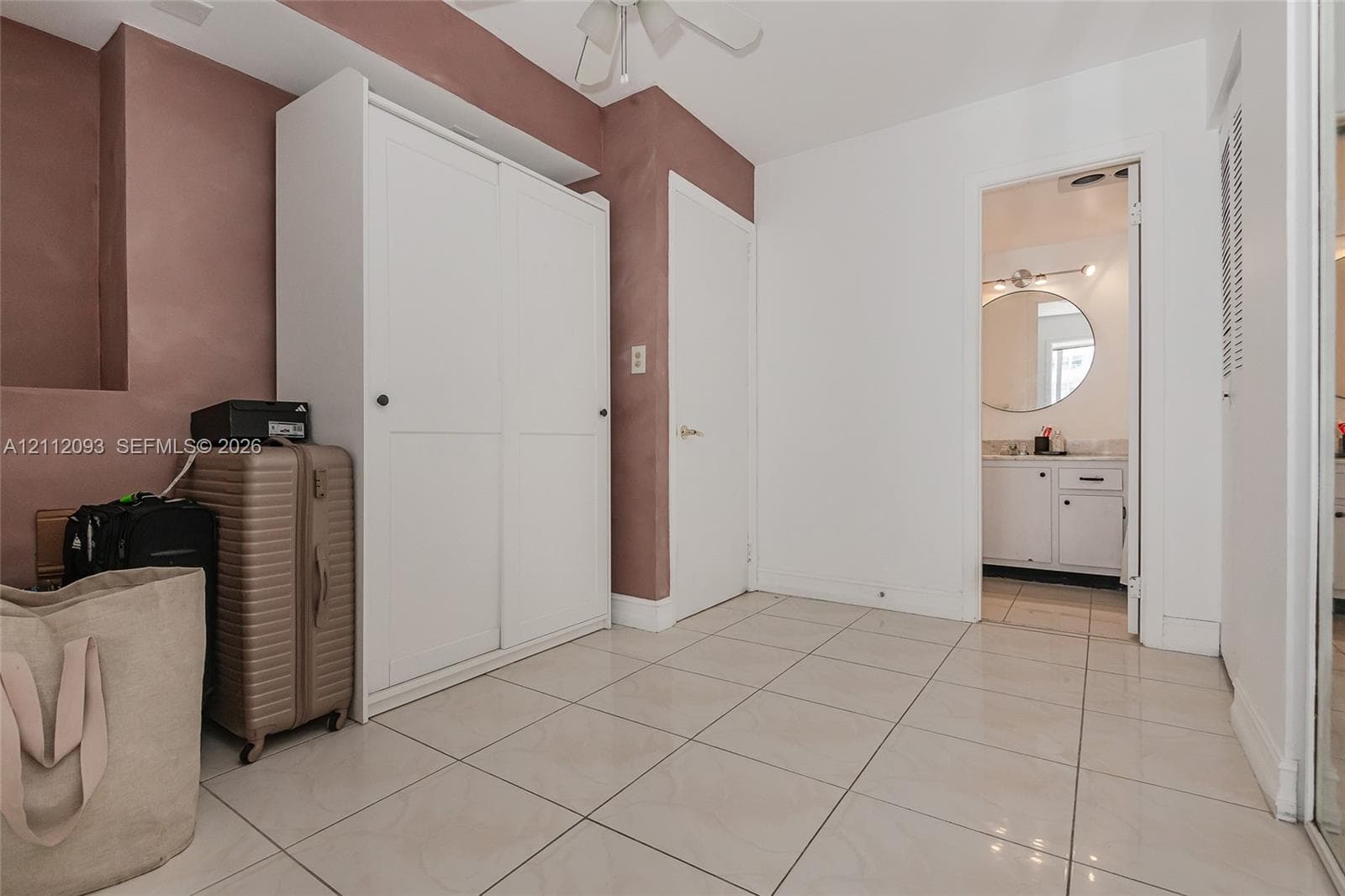 Large-format neutral floor tiling, built-in white wardrobe cabinetry, and recessed ceiling lighting