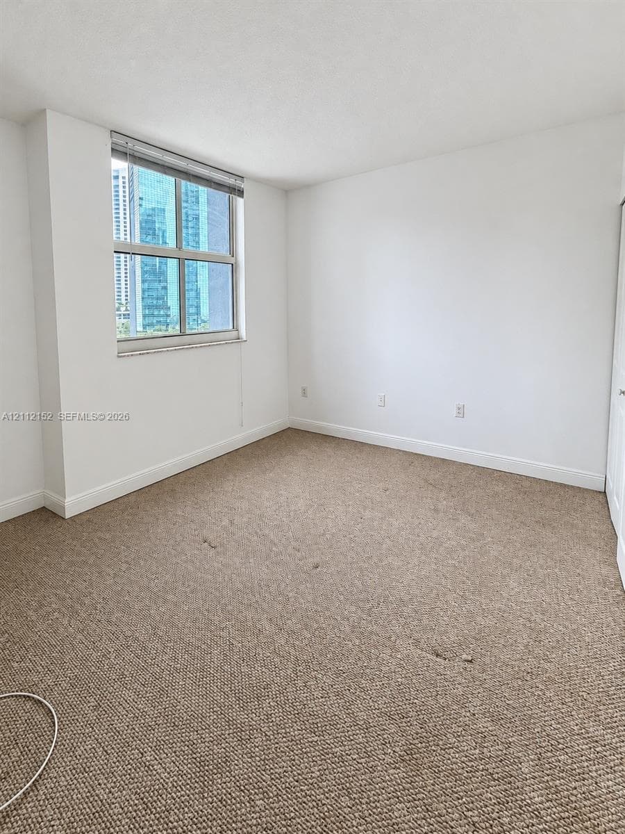 Neutral-toned wall-to-wall carpeting, window with integrated blinds, and closet with sliding doors