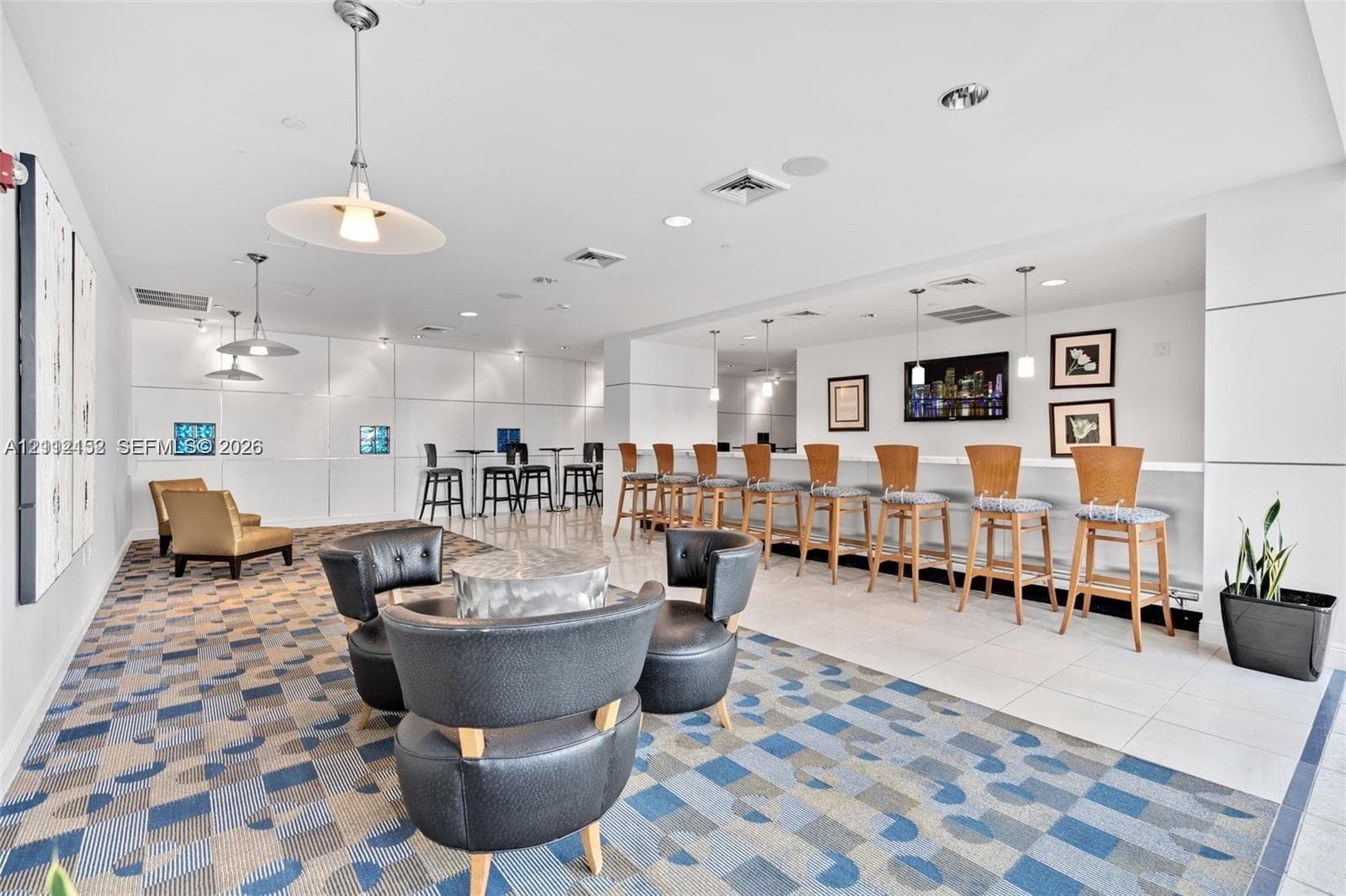 Common space featuring recessed ceiling lighting, pendant light fixtures, built-in bar counter, patterned carpeting, and tile flooring