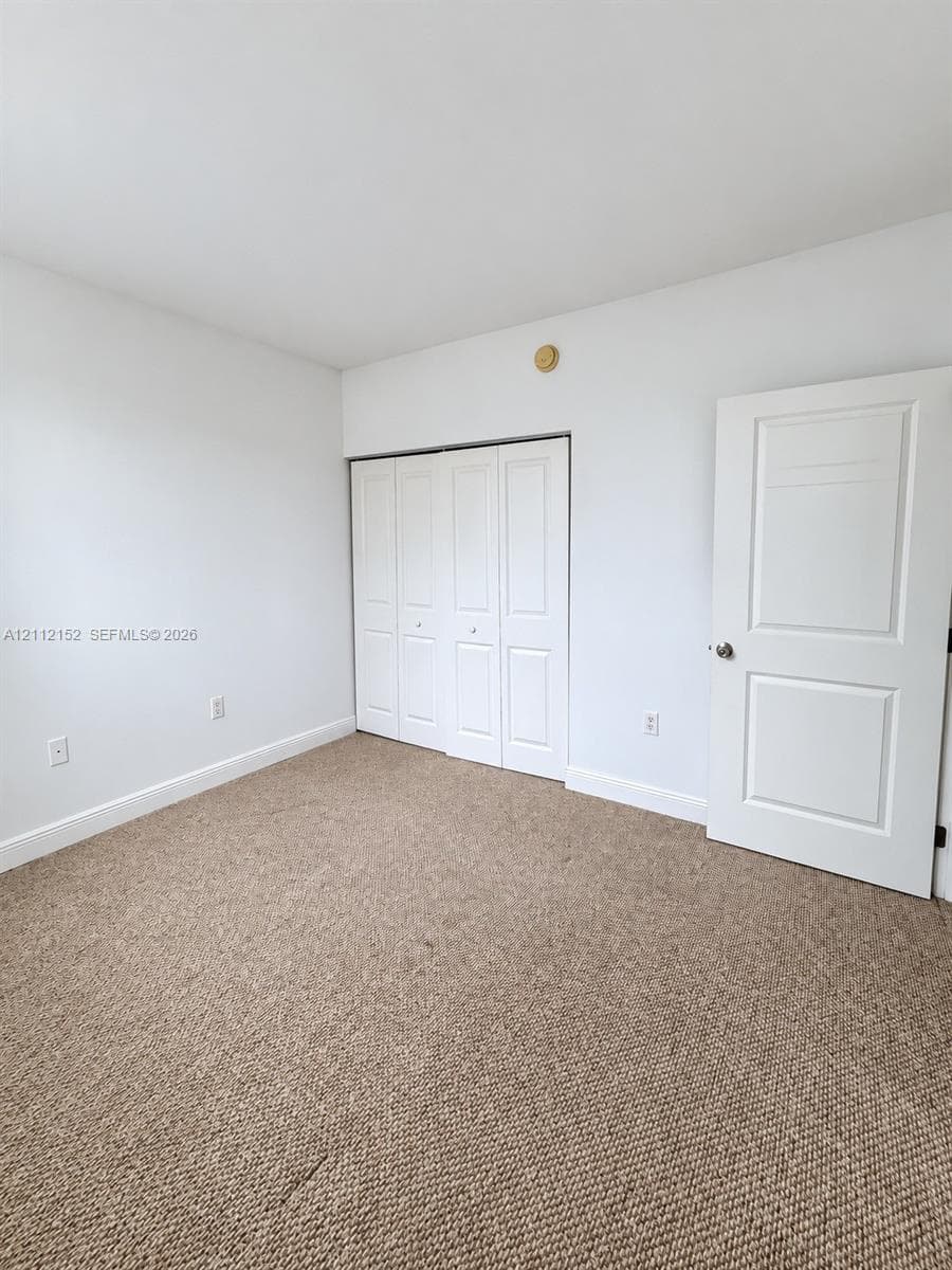 Neutral-toned carpeting, white walls, folding-panel closet doors, and a solid-core two-panel interior door