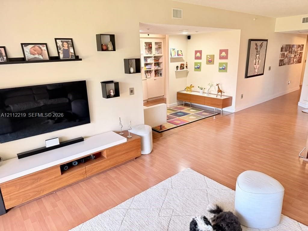 Built-in floor-to-ceiling cabinetry with glass-panel doors, recessed ceiling lighting, wood-finish flooring, and wall-mounted floating shelves