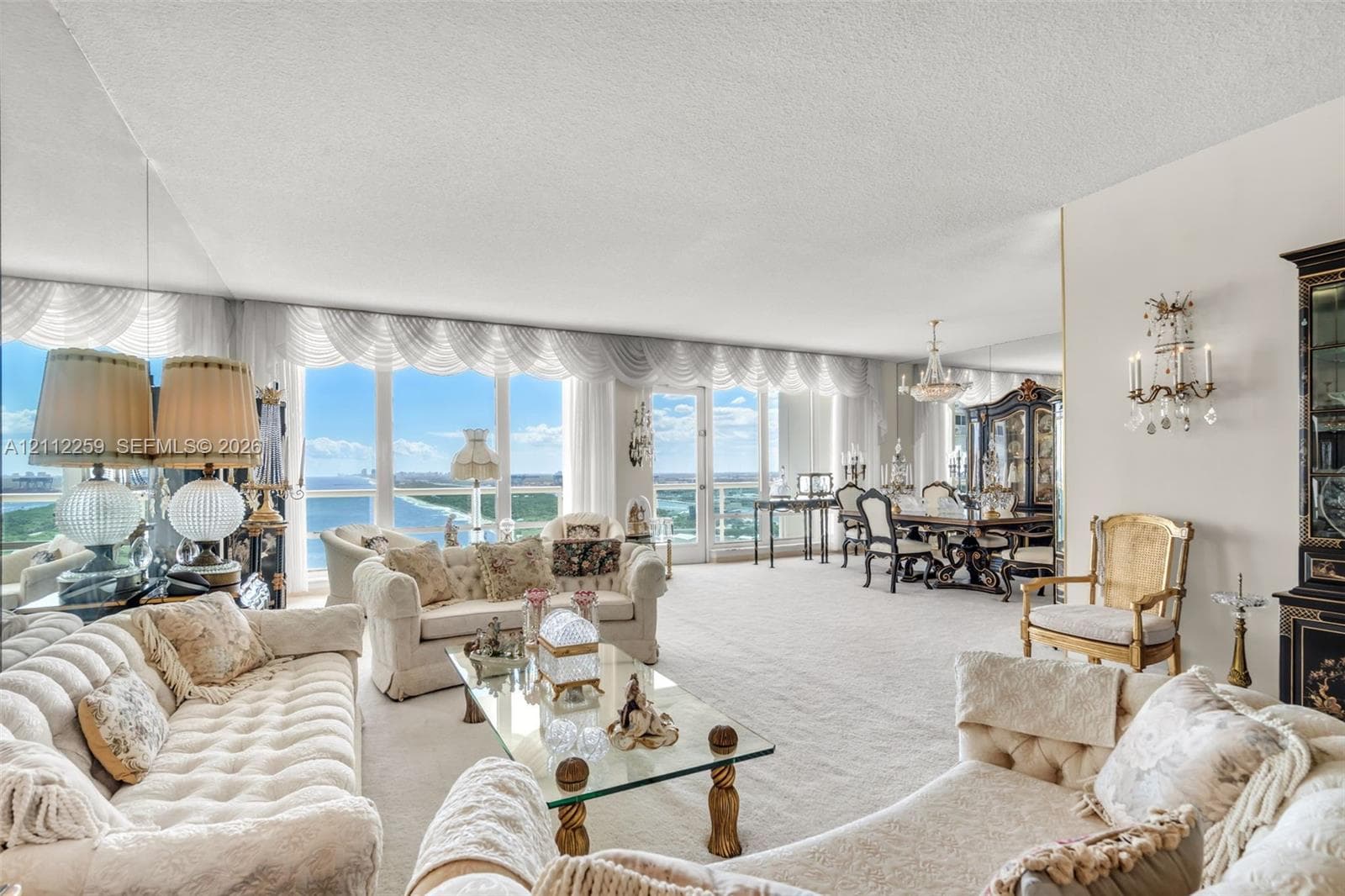 Floor-to-ceiling windows, mirrored wall accents, wall-mounted decorative sconces, and neutral carpeting