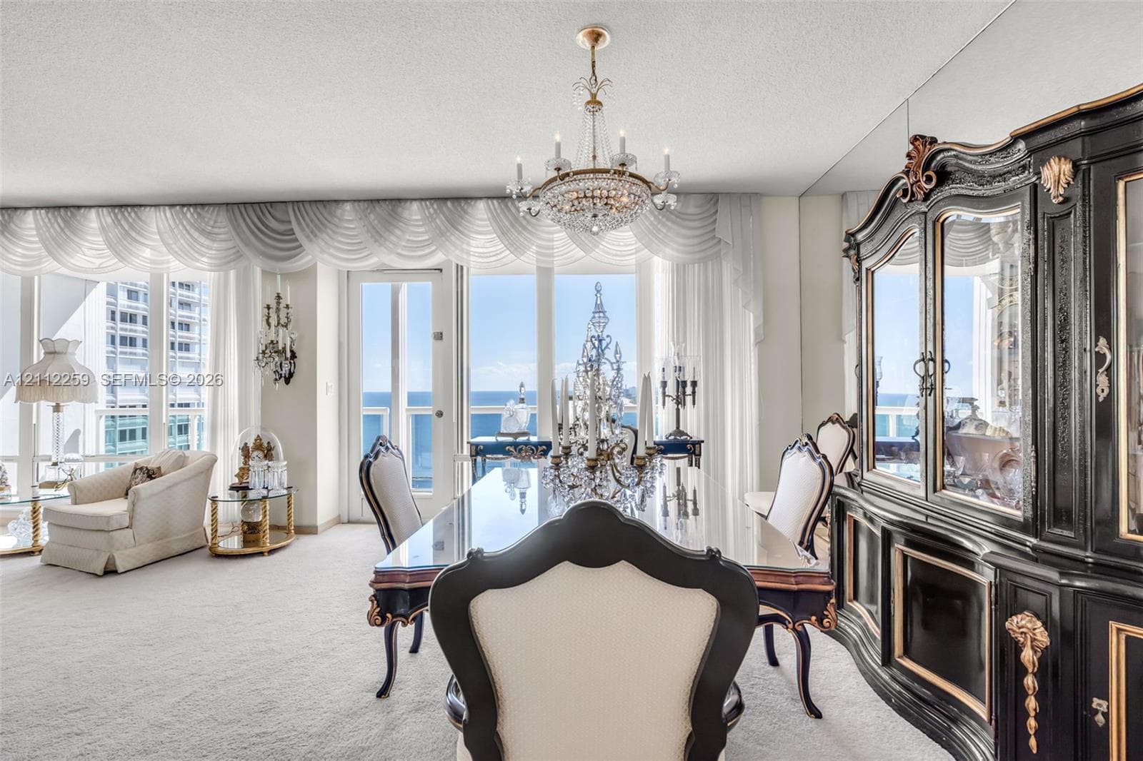 Floor-to-ceiling windows, crystal chandelier, mirrored wall paneling, and a glass-paneled door