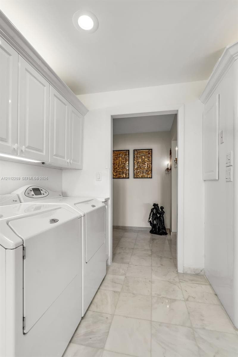 Laundry area featuring white shaker-style wall cabinetry, stone-finish tile flooring, and recessed ceiling lighting