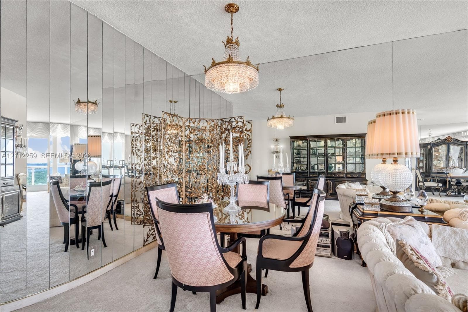 Floor-to-ceiling mirrored wall paneling, crystal tiered chandelier, and built-in glass-front cabinetry