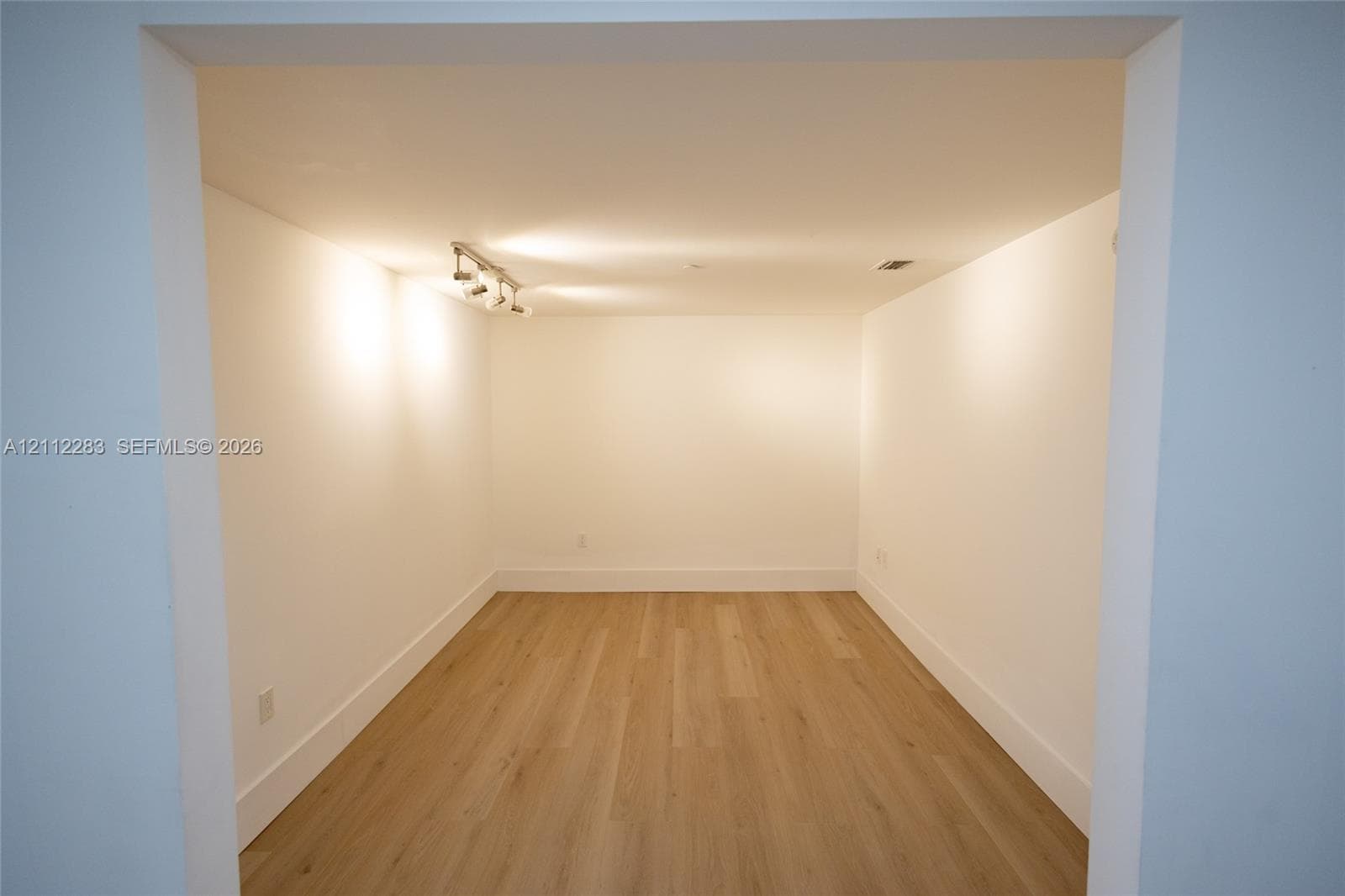 Interior space featuring wood-finish flooring, smooth wall surfaces, and ceiling-mounted track lighting