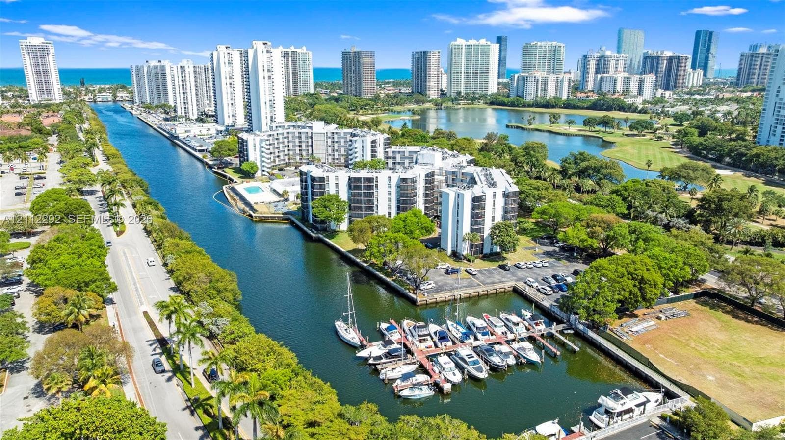 Aerial perspective of waterfront mid-rise buildings featuring a private deep-water dock, integrated boat slips, paved parking areas, and mature landscape elements
