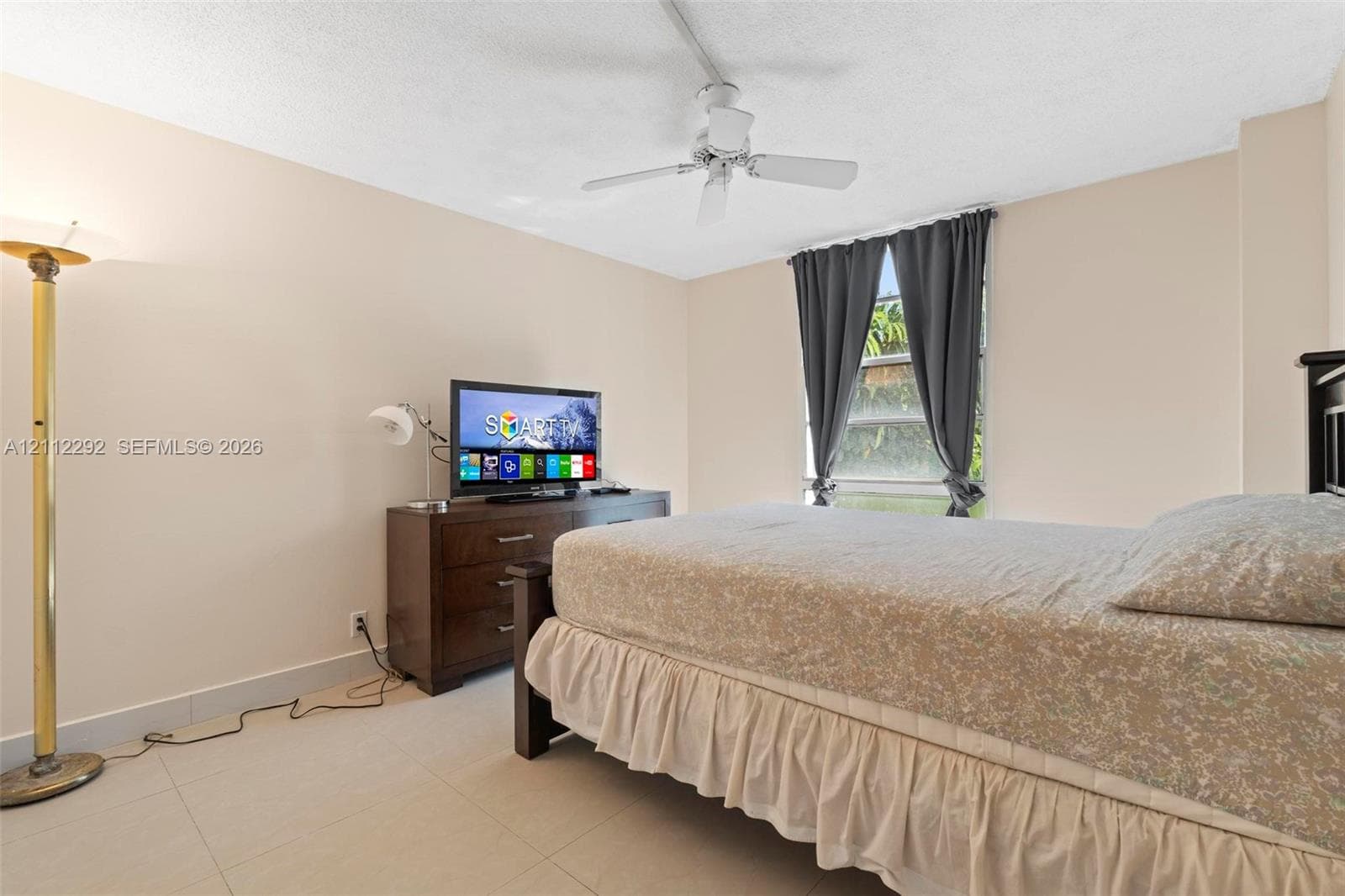 Room featuring light-toned neutral walls, polished tile flooring, and a ceiling-mounted fan