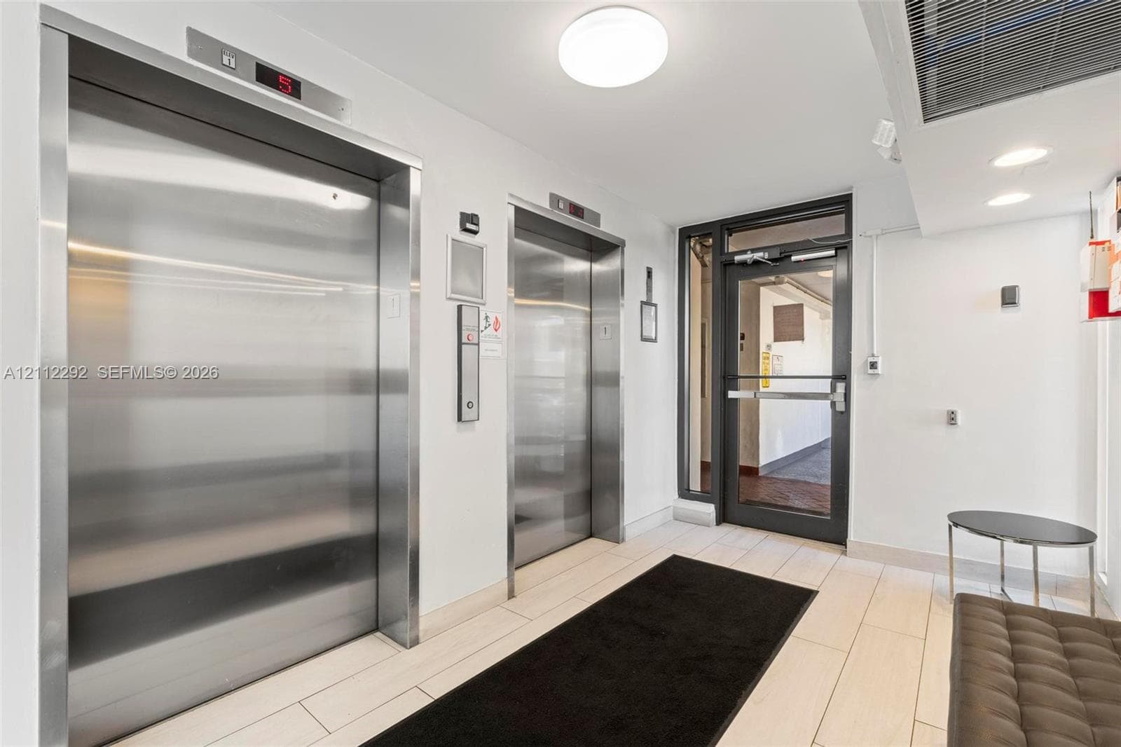 Common area featuring dual stainless steel elevators, recessed lighting, and tile flooring