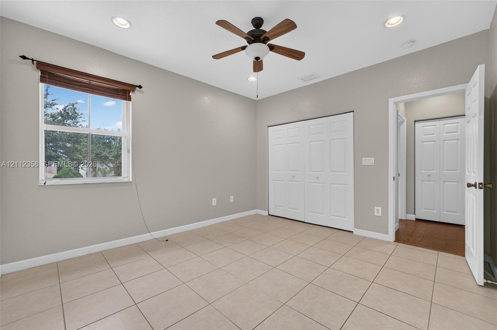 Room featuring tile flooring, neutral wall paint, recessed lighting, a ceiling fan with integrated light fixture, and double-panel closet doors