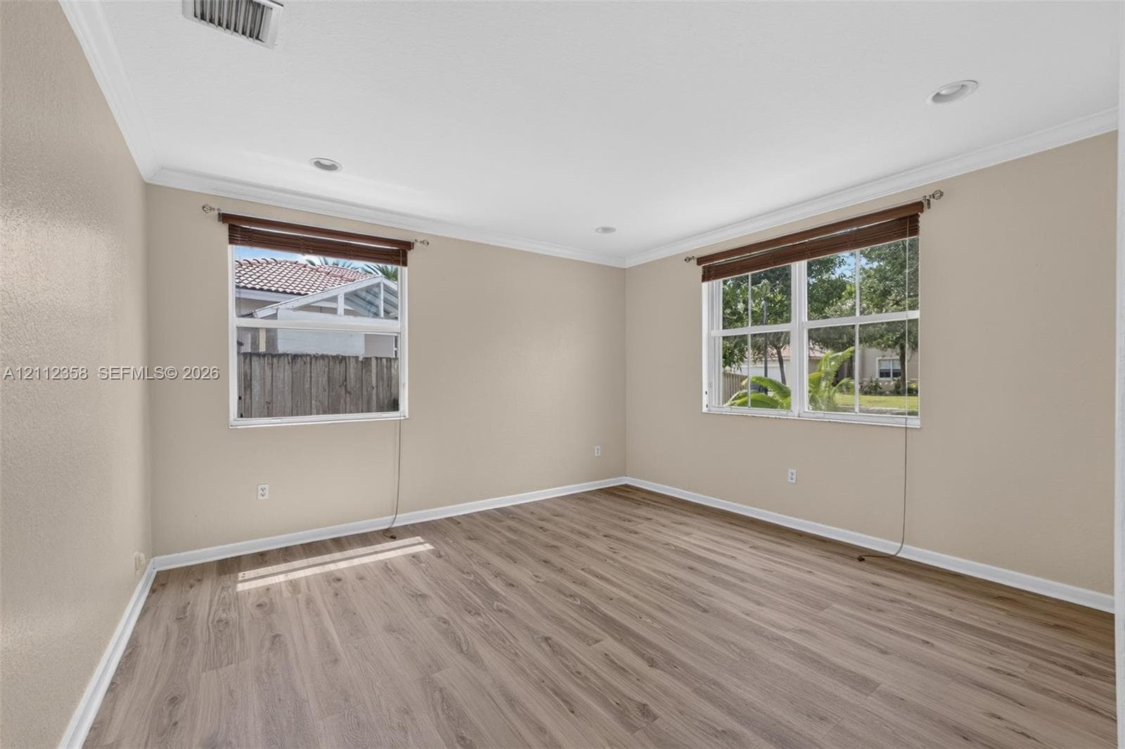 Neutral interior featuring wood-finish flooring, crown molding, recessed lighting, and multi-pane windows
