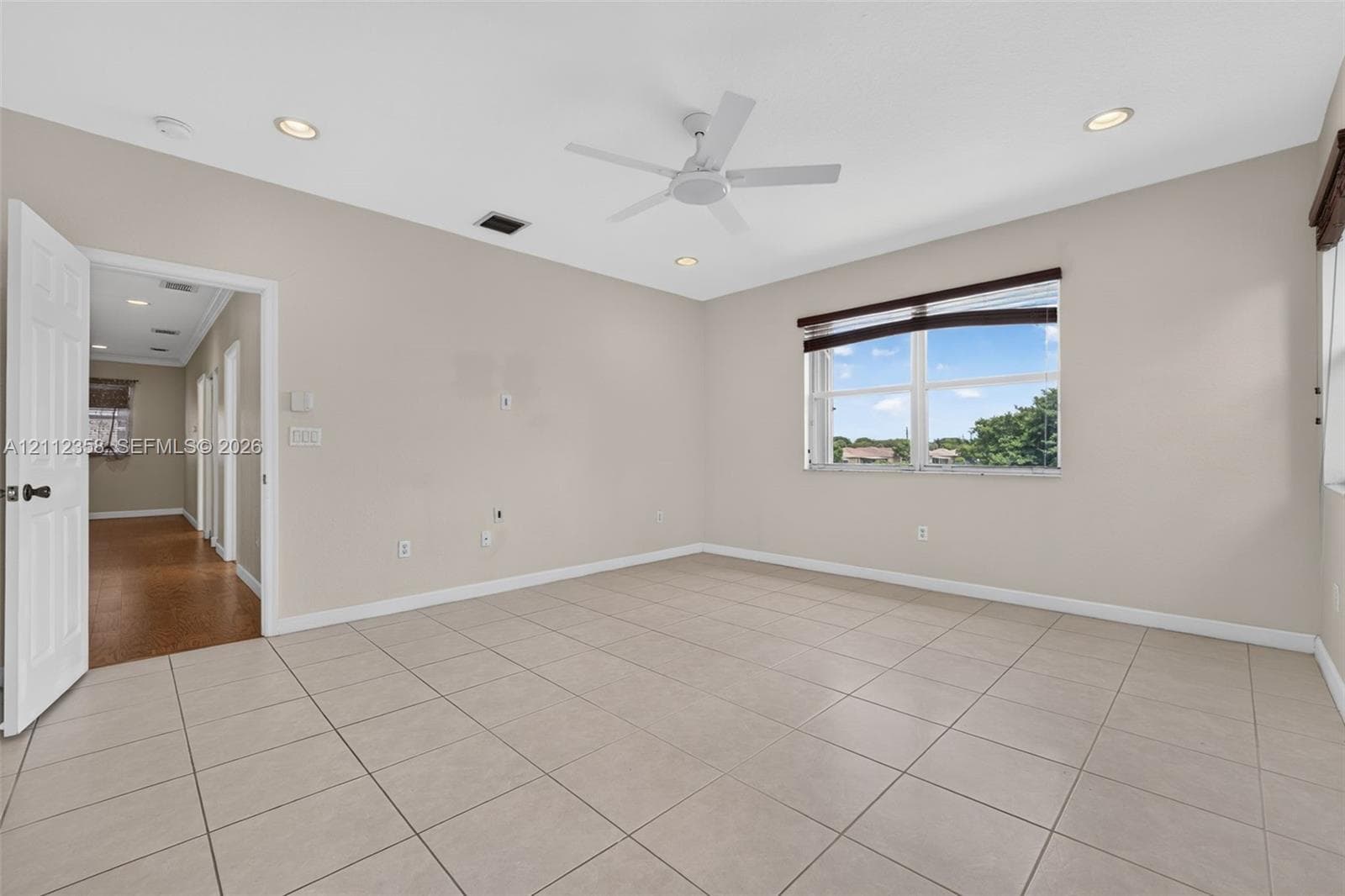 Spacious room featuring neutral tile flooring, recessed lighting, a white ceiling fan, and a single-pane window