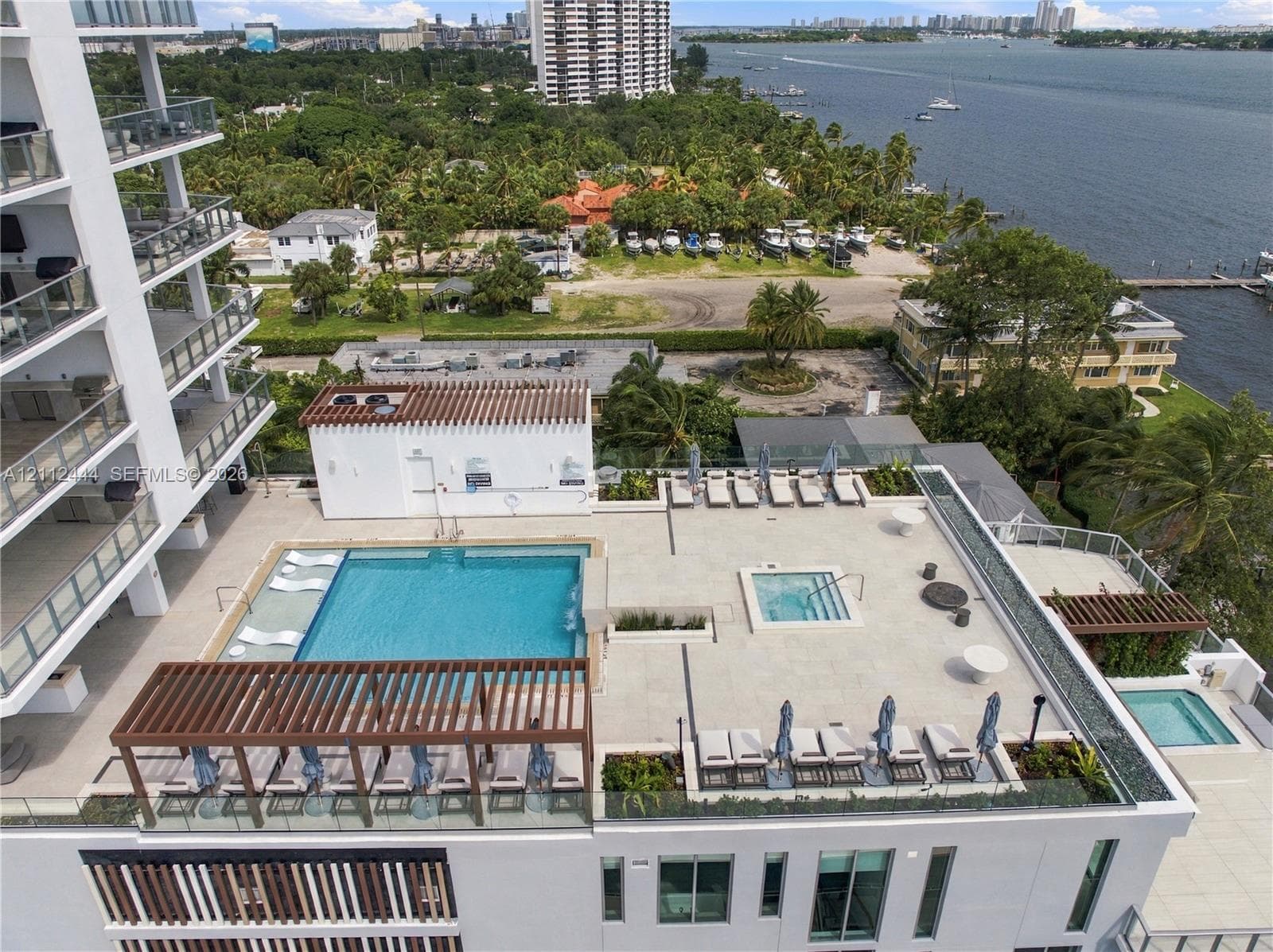 Elevated terrace featuring a pool, integrated spa, wood-slat pergola, and stone-finish decking