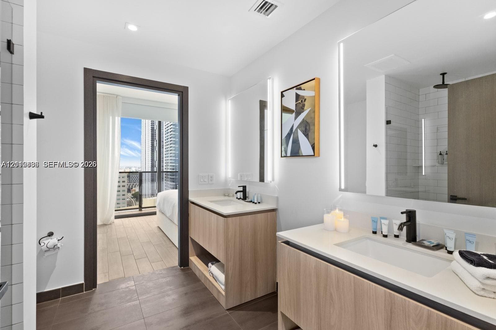 Dual wood-finish floating vanities featuring stone-style countertops, rectangular undermount sinks, matte black fixtures, and integrated LED-backlit mirrors