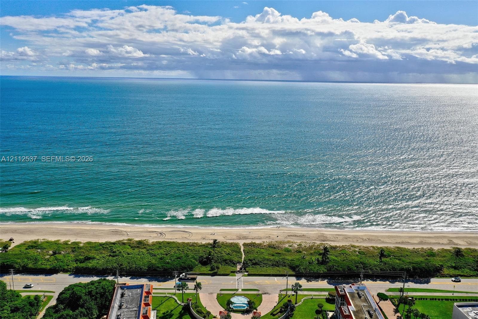 Direct oceanfront exposure with panoramic water scenery, sandy beach access, and coastal landscaping