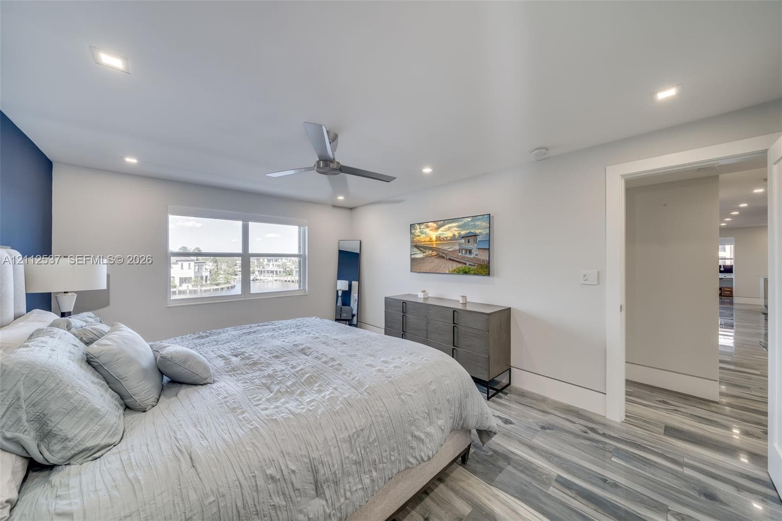 Bedroom featuring multi-tonal wood-finish flooring, recessed lighting, a modern ceiling fan, and a dual-pane window
