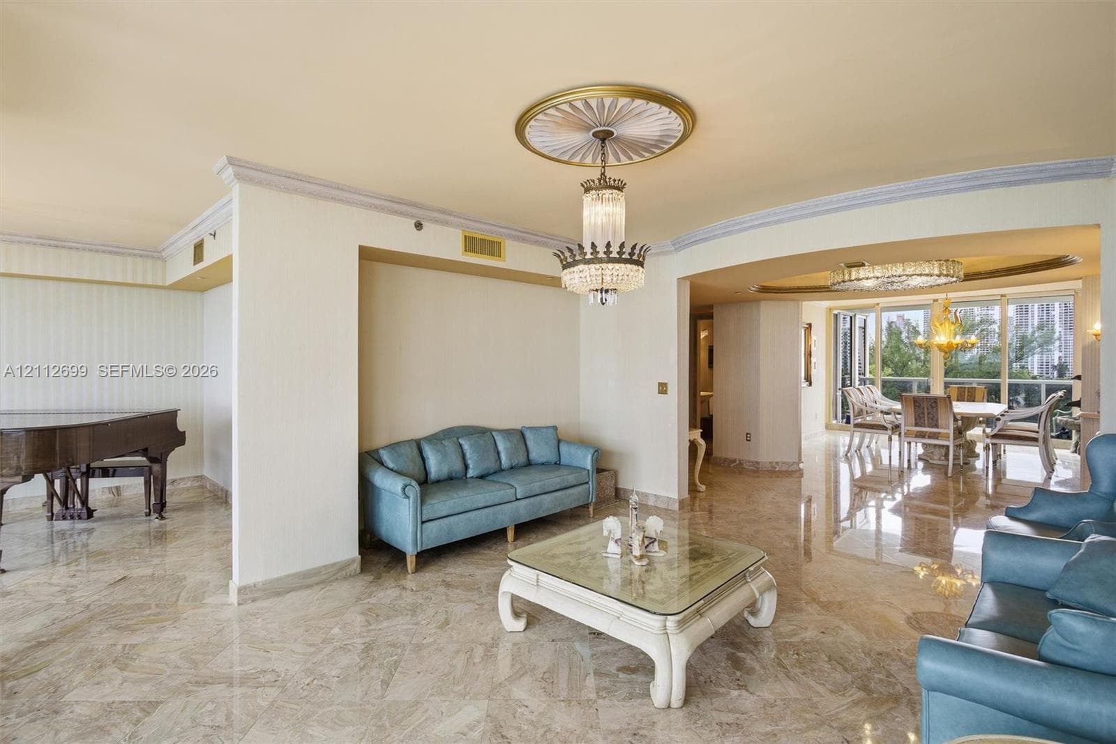 Polished stone flooring, ornate ceiling medallion with a crystal tiered chandelier, multi-pane floor-to-ceiling windows, and recessed ceiling lighting