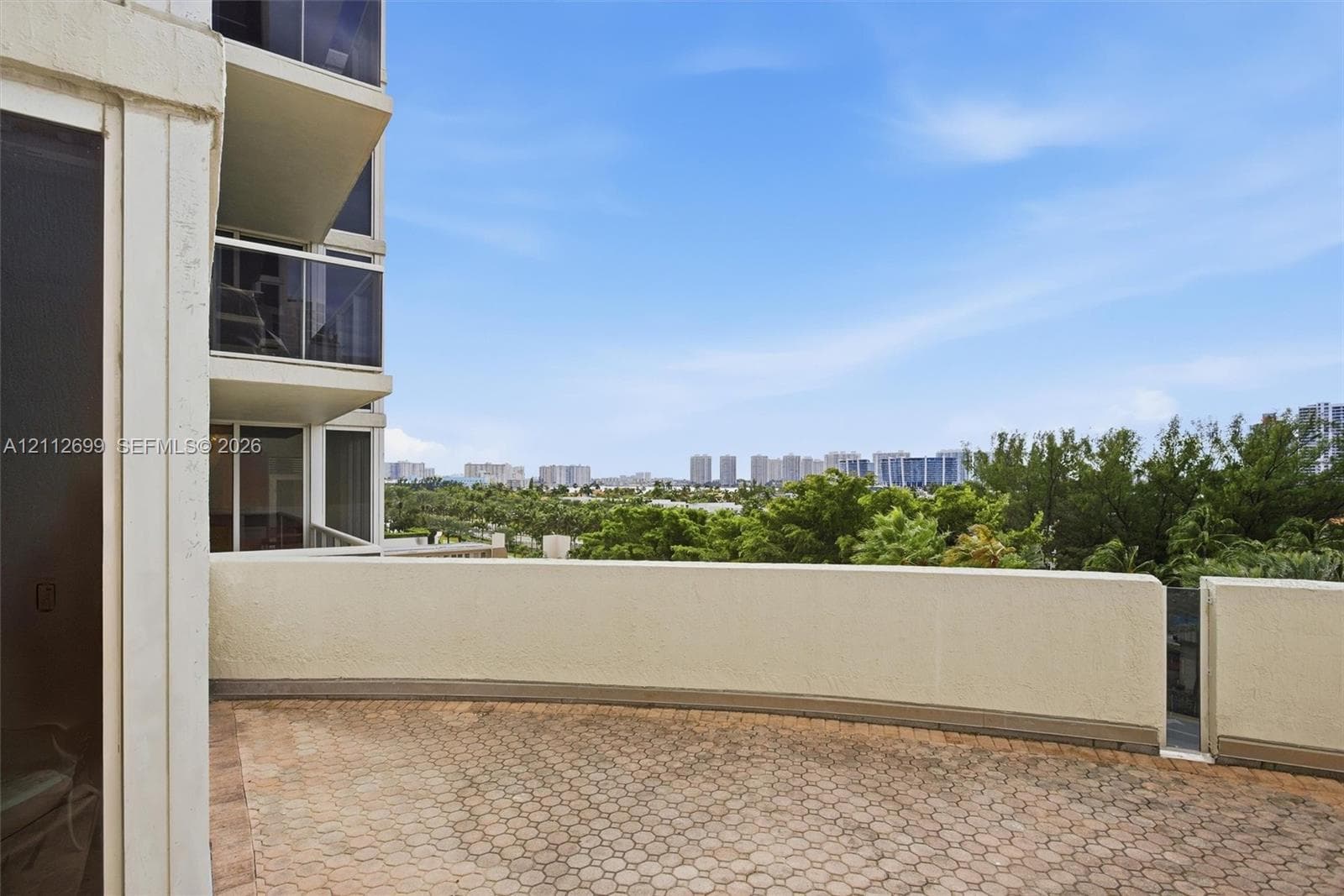 2nd expansive private terrace featuring patterned paver flooring, perimeter walls with gorgeous sunset views.