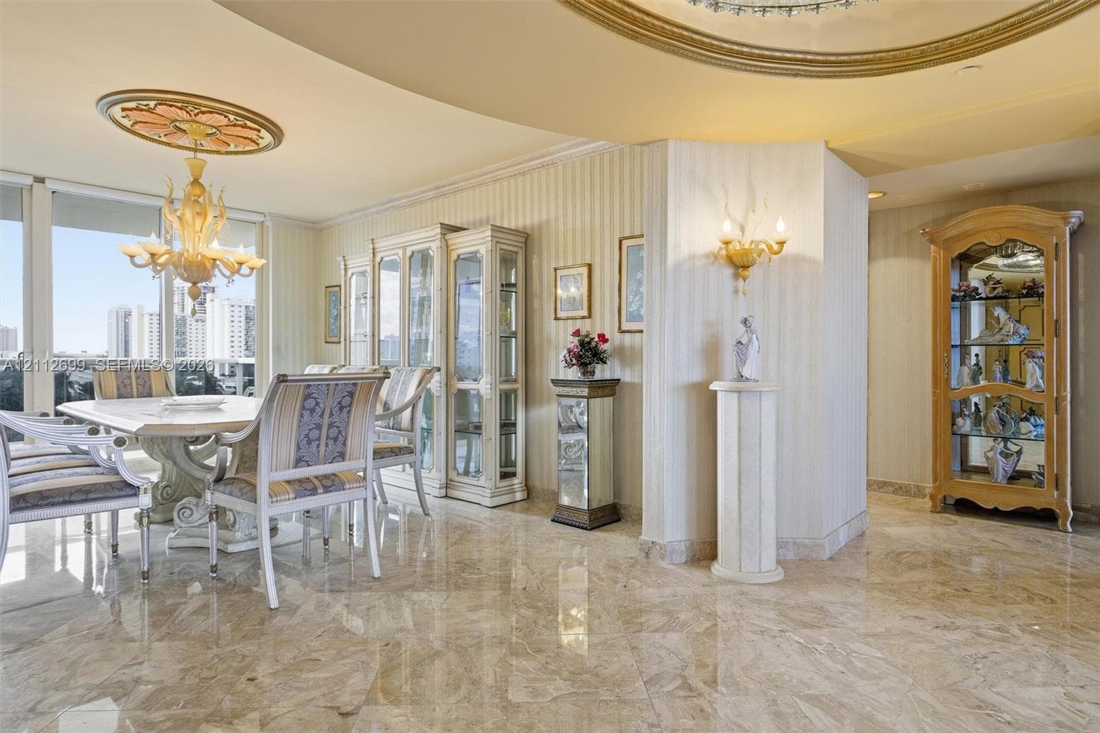 Polished stone flooring, custom architectural ceiling molding, decorative ceiling medallion, built-in cabinetry, and wall-mounted sconces