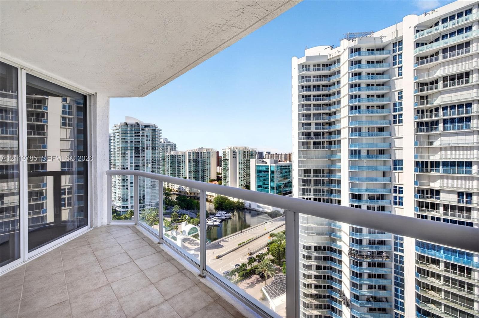 Covered balcony featuring tile flooring and a glass-paneled railing