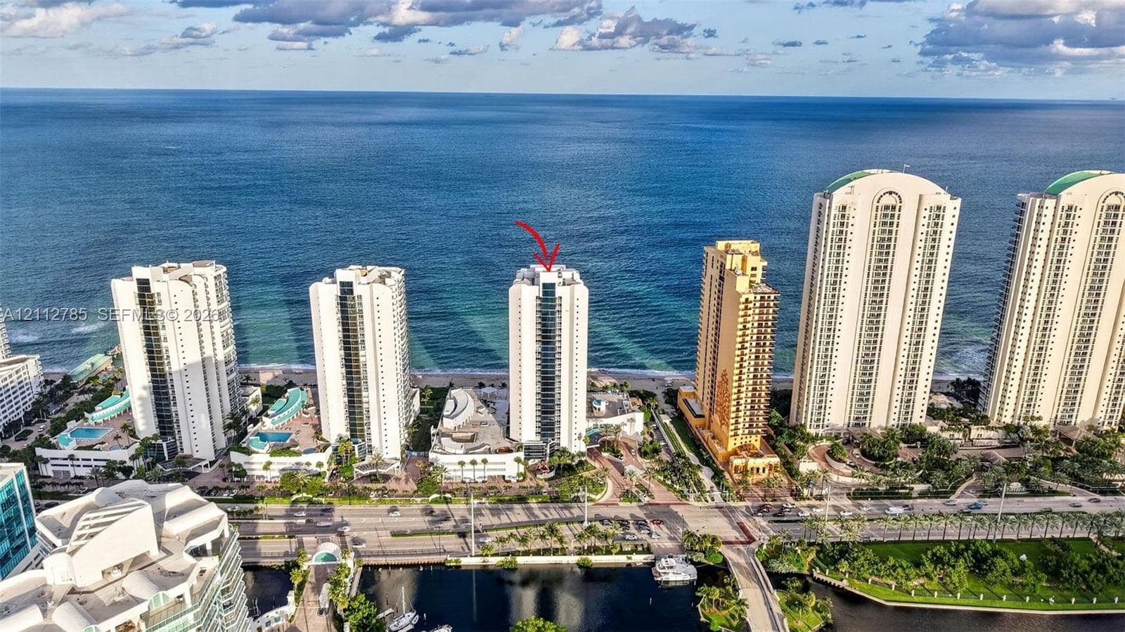 Aerial perspective of oceanfront high-rise featuring expansive water frontage and coastal positioning