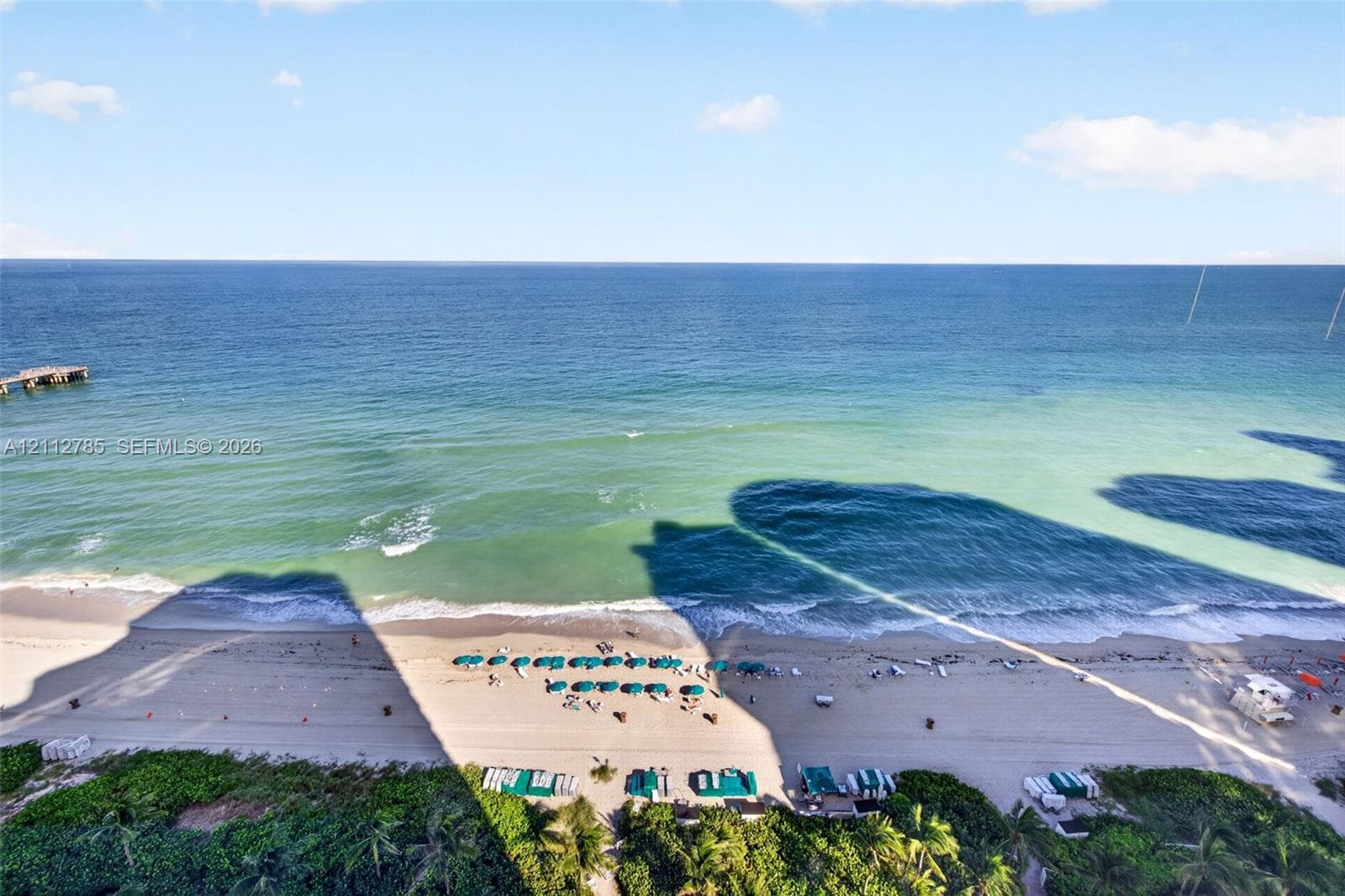 Direct oceanfront exposure featuring expansive sandy shoreline, turquoise water, and a wooden pier