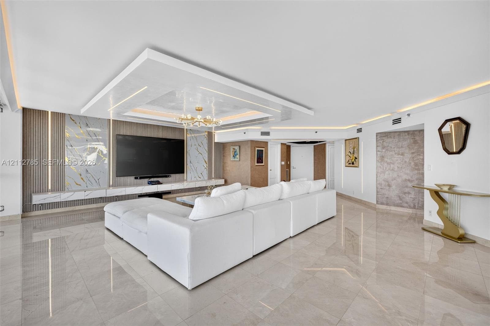 Polished stone flooring, custom tray ceiling with integrated recessed lighting, and wall-to-wall stone slab media center with vertical LED accent panels