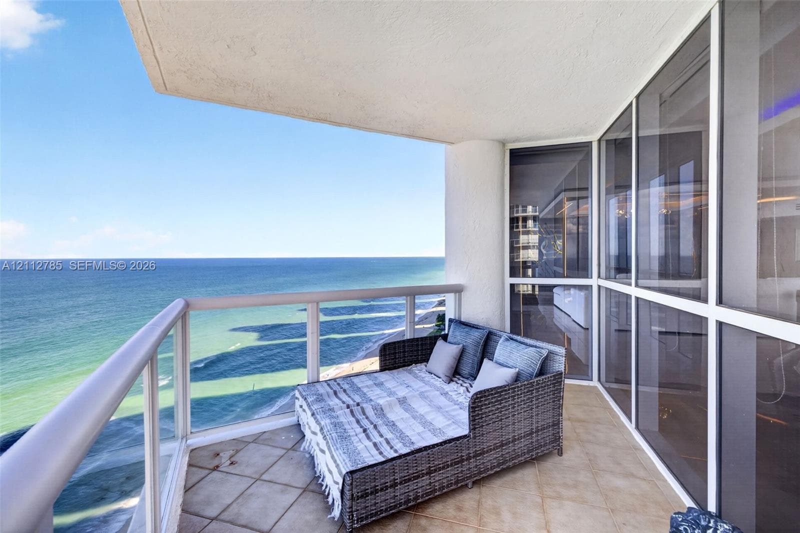 Private balcony featuring tile flooring, metal and glass railings, and floor-to-ceiling glass paneling overlooking the ocean
