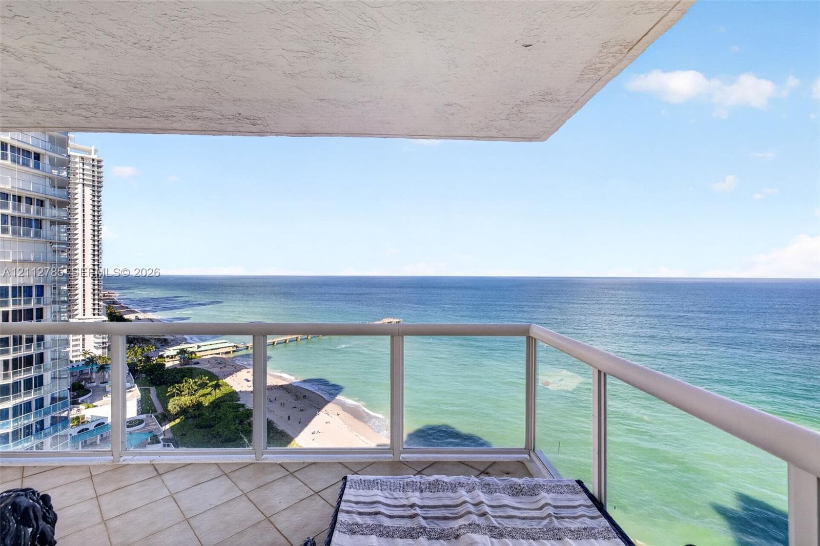 Covered balcony featuring tile flooring and a glass-paneled railing