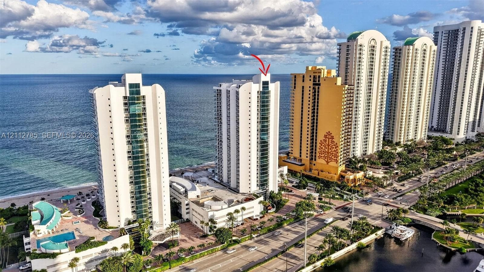 High-rise coastal architecture featuring glass-paneled balconies and direct proximity to the oceanfront