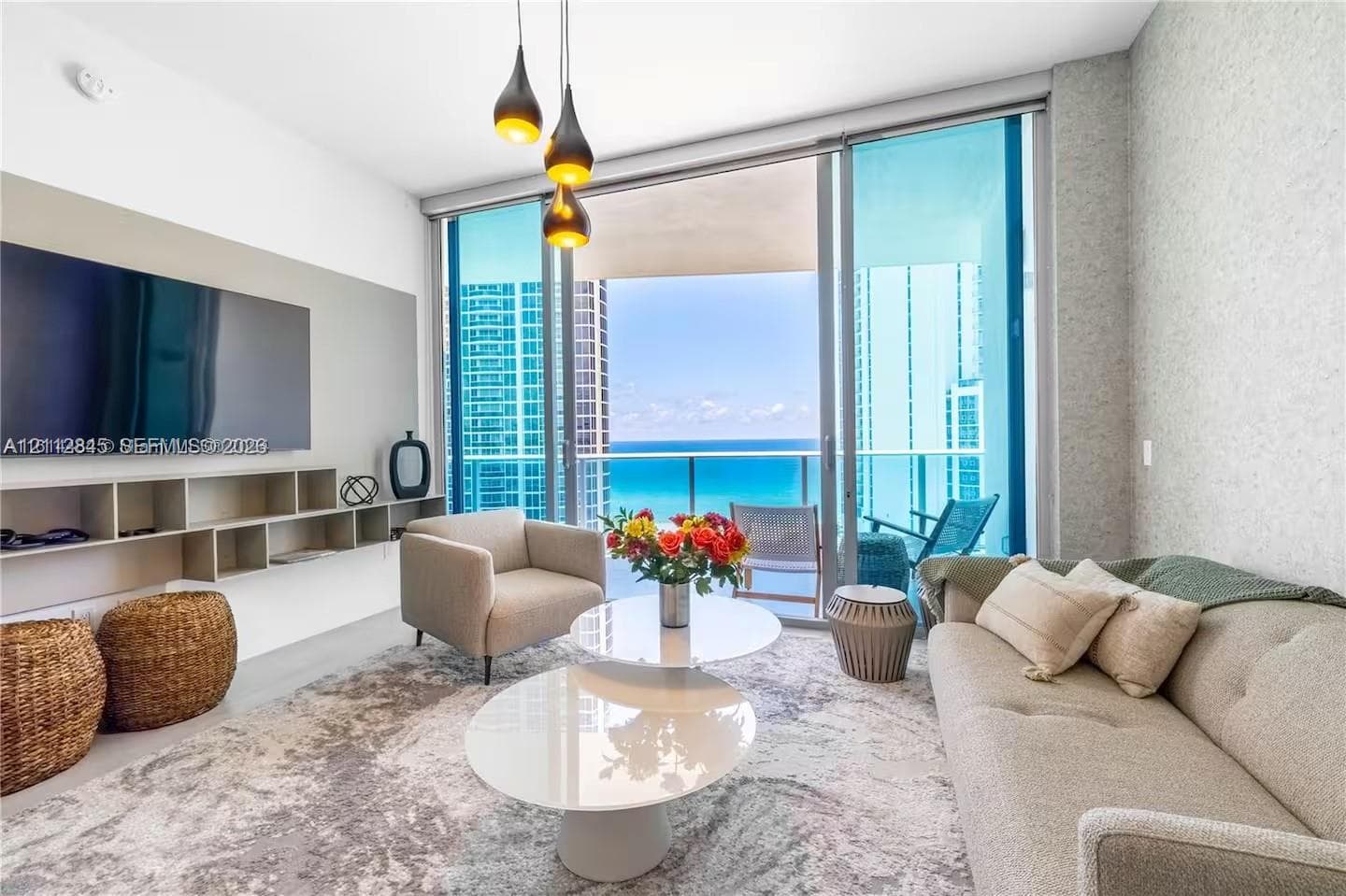 Floor-to-ceiling glass doors, custom built-in cabinetry, modern pendant lighting, textured wall finish, and a glass-paneled balcony