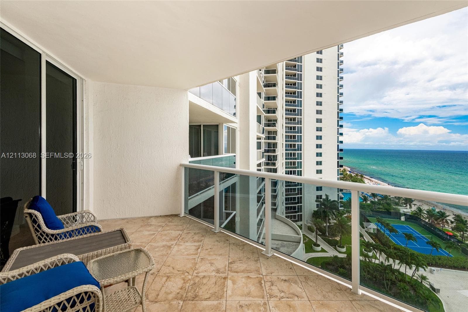 Covered balcony featuring tile flooring and a glass panel railing