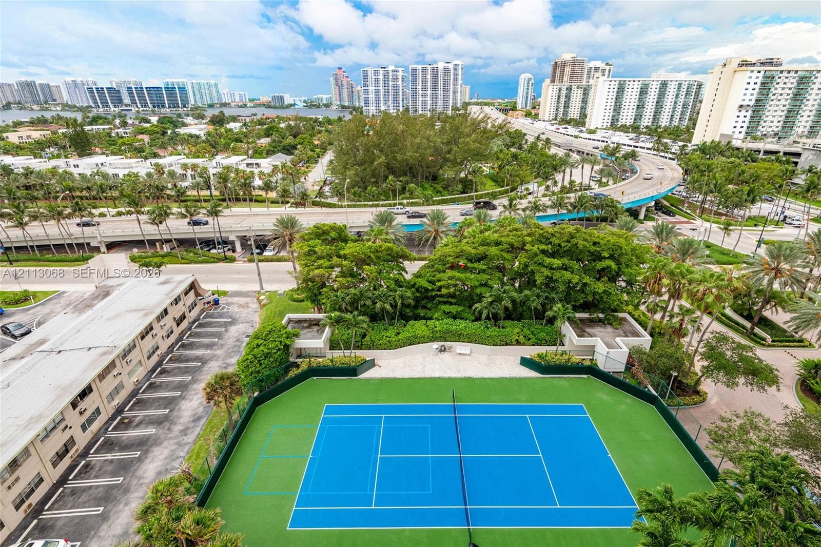 Tennis court with a painted hard surface, perimeter fencing, and an integrated paved seating area