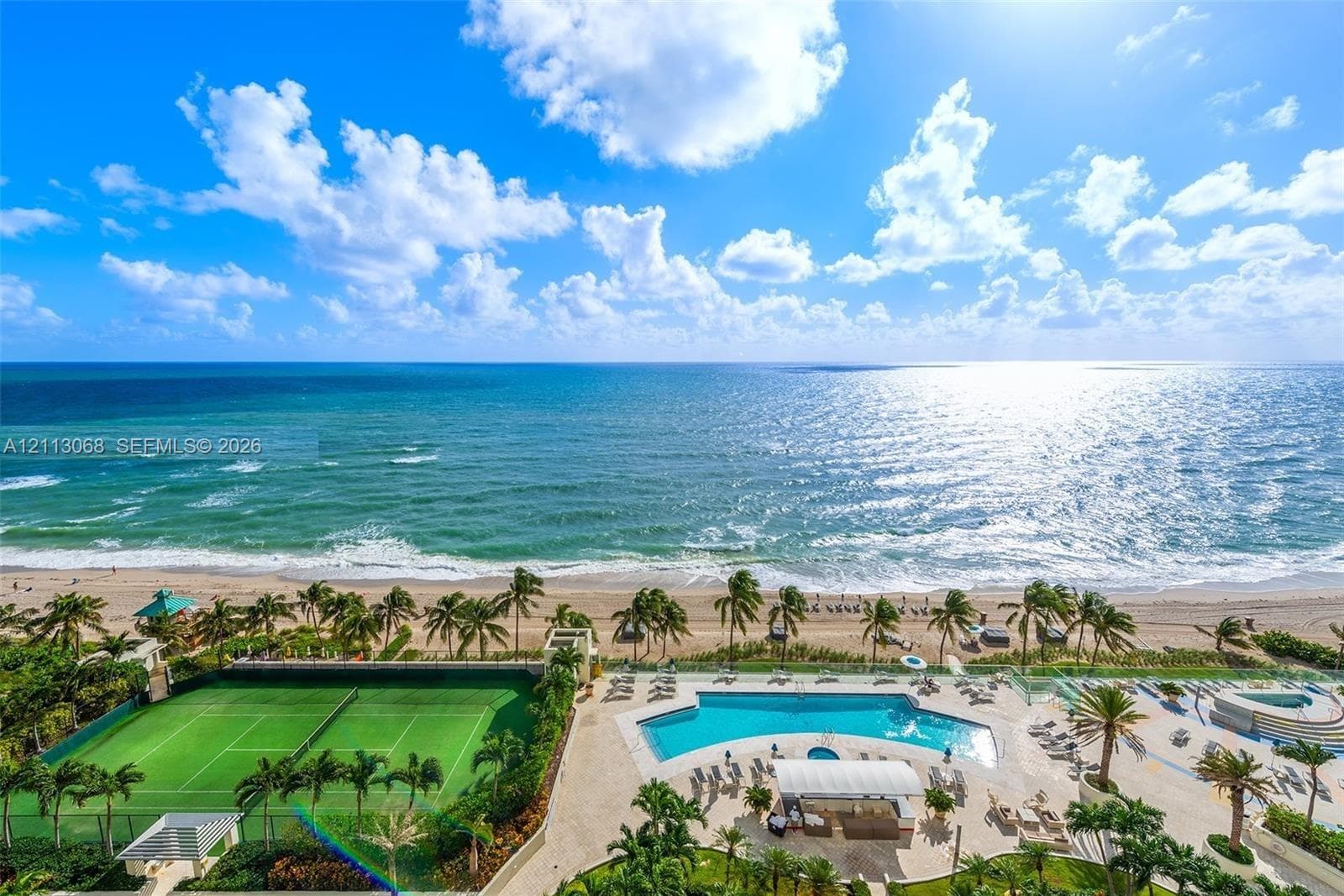 Oceanfront property featuring a swimming pool, two tennis courts, and direct access to a sandy beach
