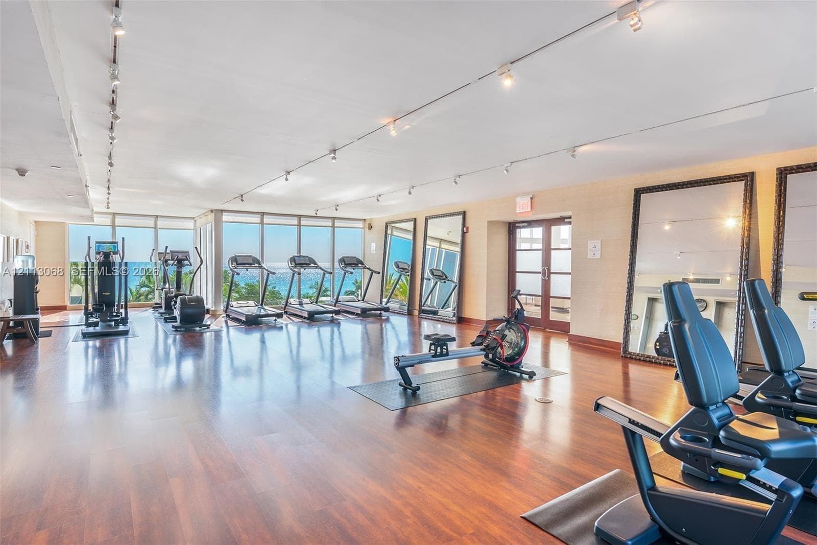 Fitness center featuring wood-finish flooring, floor-to-ceiling windows, track lighting, and full-length wall mirrors