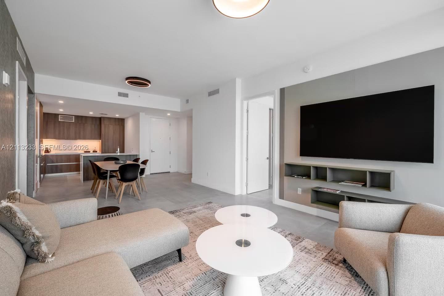 Open-concept interior featuring large-format tile flooring, recessed ceiling lighting, and a custom built-in media console