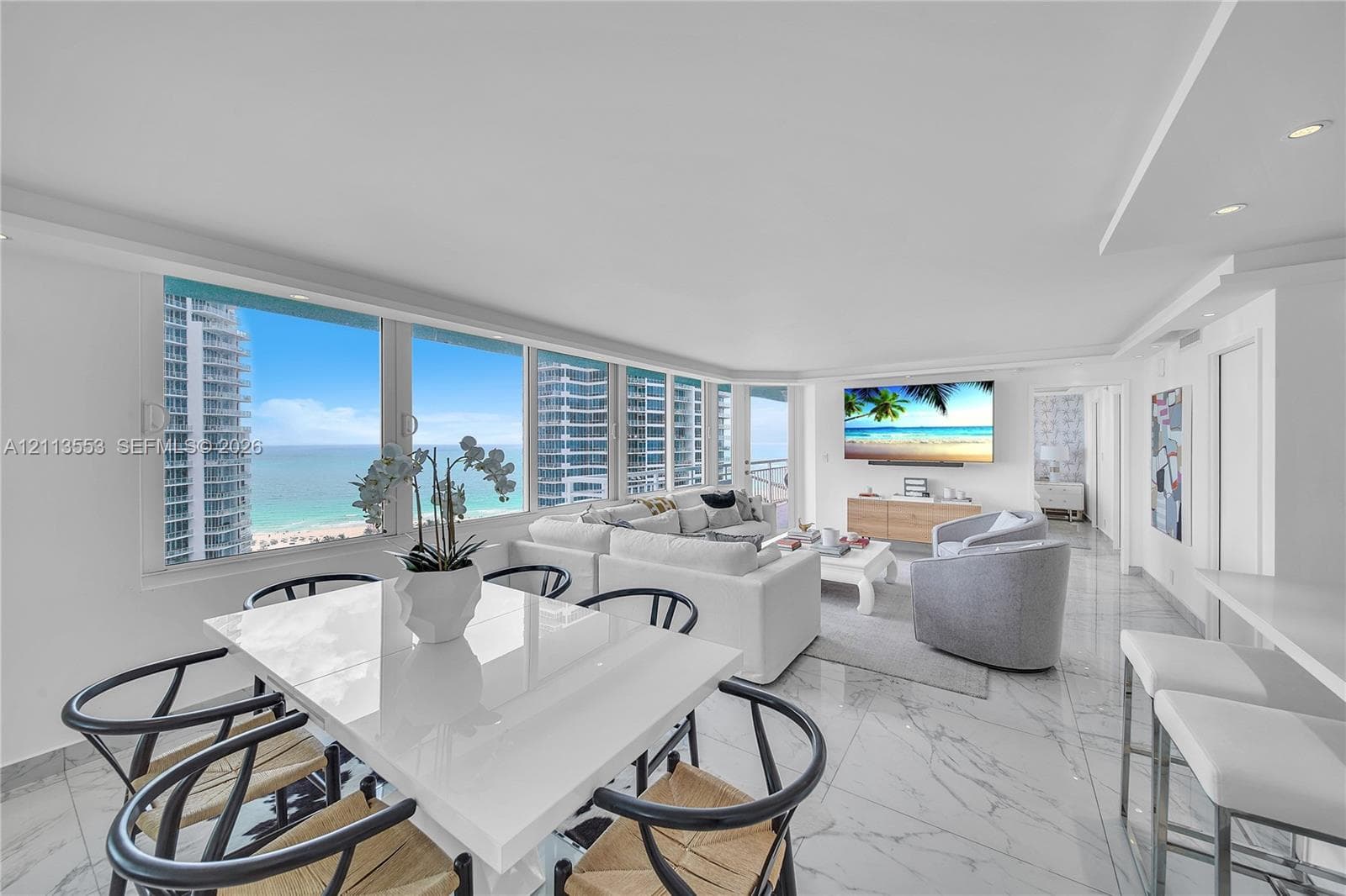 Open-concept interior featuring floor-to-ceiling windows, natural stone-finish flooring, recessed lighting, and expansive ocean scenery