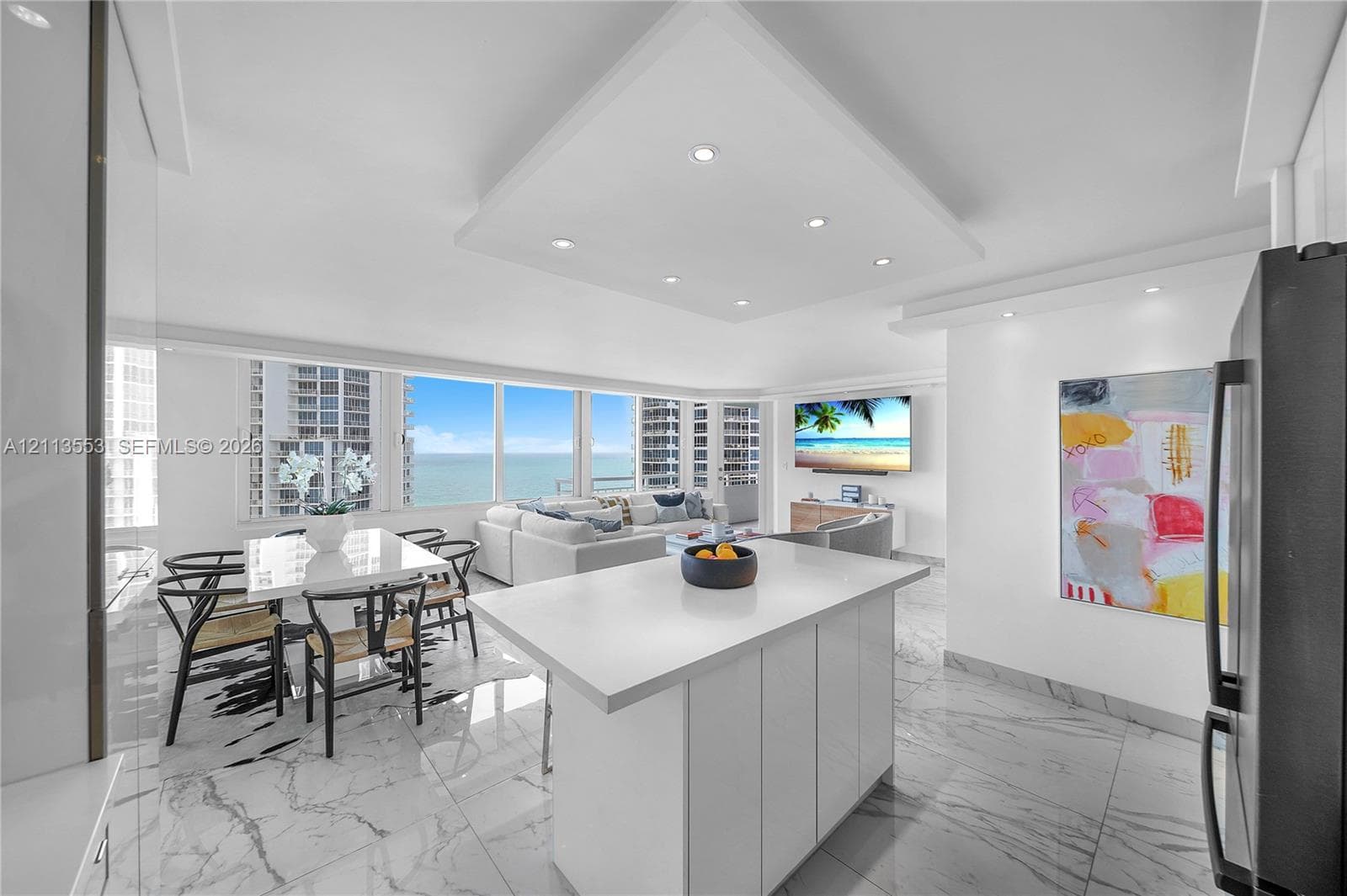 Open-concept space featuring expansive floor-to-ceiling windows, white cabinetry, a center island with a stone-finish countertop, and polished flooring with a marble-style pattern
