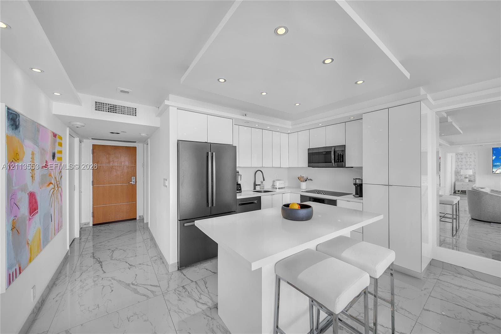 Modern kitchen featuring flat-panel white cabinetry, a center island with a quartz countertop, recessed ceiling lighting, and tile flooring with a stone-finish pattern