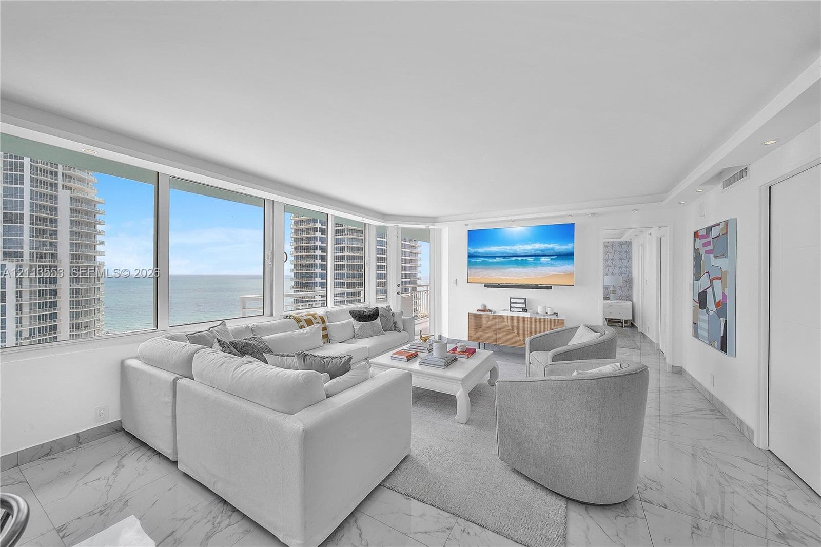 Floor-to-ceiling windows, stone-finish tile flooring, recessed lighting, and wall-mounted television console