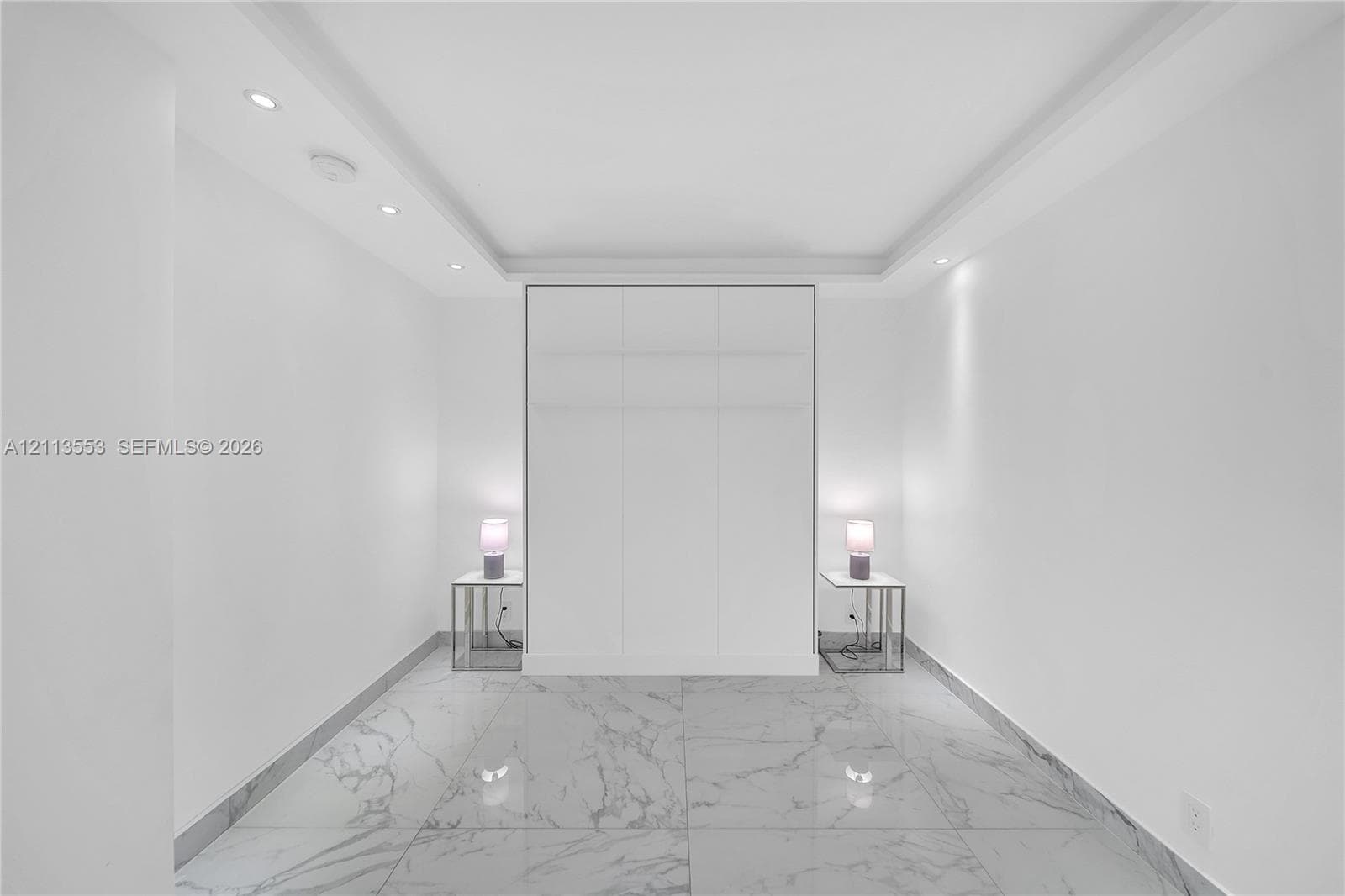 Large-format stone-look flooring, recessed ceiling lighting, tray ceiling architecture, and floor-to-ceiling built-in cabinetry