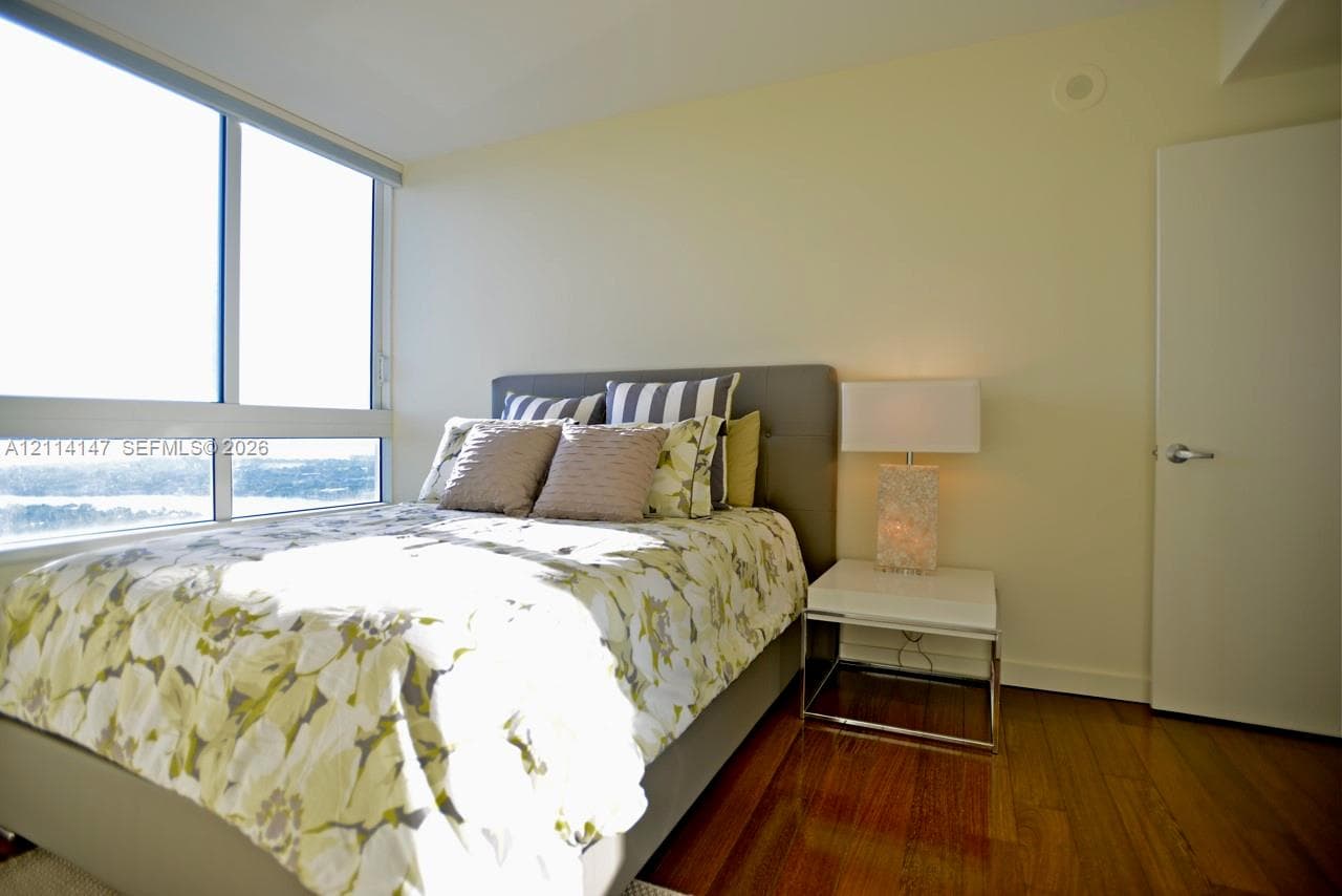 Floor-to-ceiling windows, wood-finish flooring, and neutral painted walls