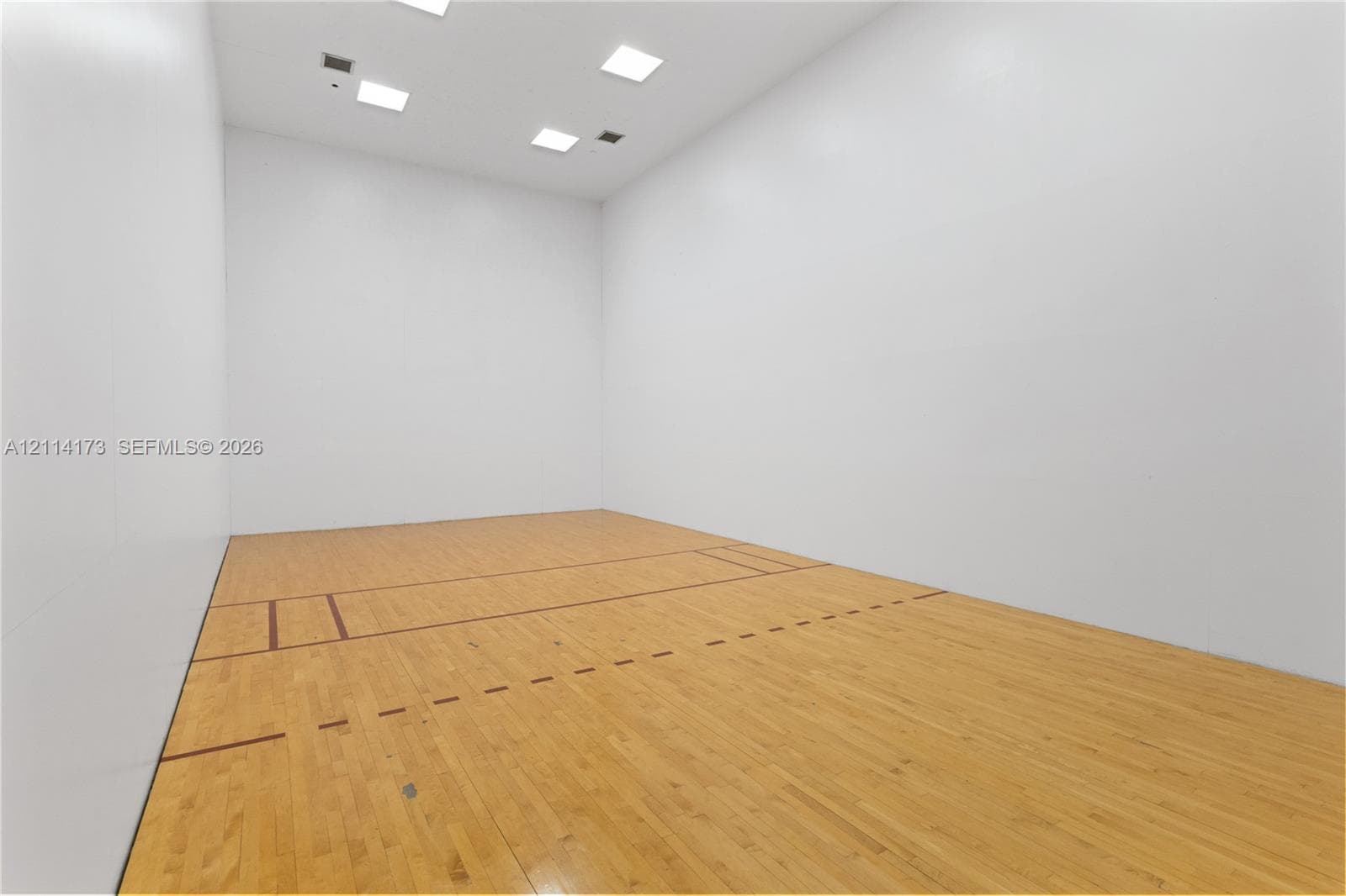 Recreational court featuring smooth panel walls, wood-finish flooring with court markings, and recessed ceiling lighting